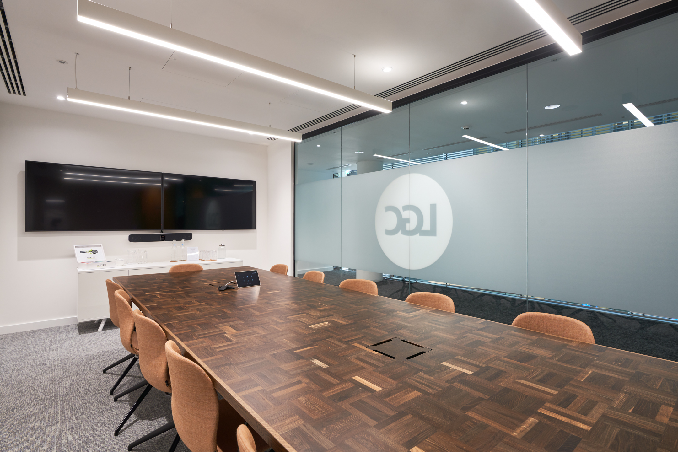 LGC boardroom with integrated tech setup and custom wood meeting table, paired with upholstered chairs supplied by Platfform.