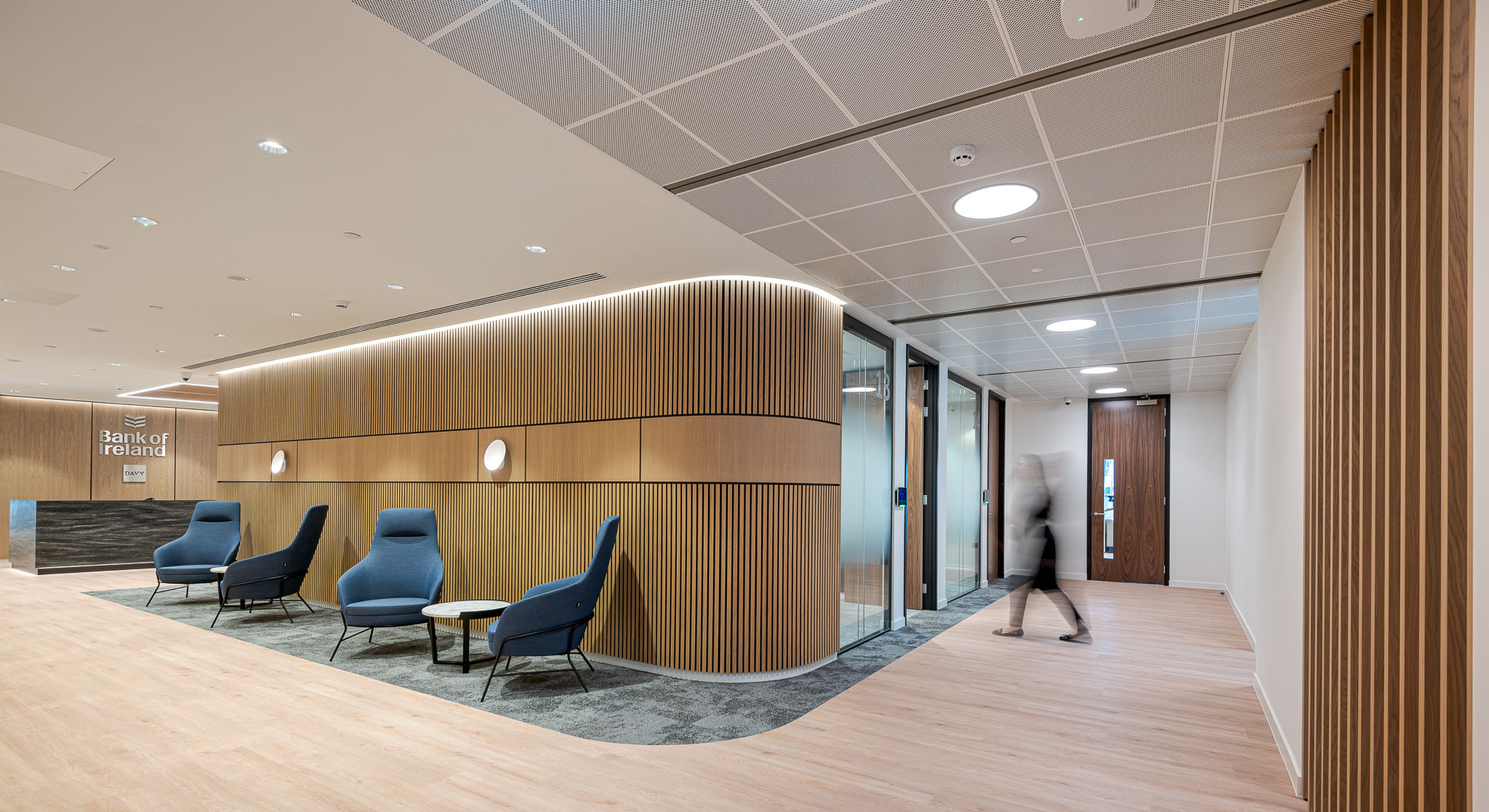 Bank of Ireland waiting area with blue lounge chairs and marble side tables, designed to balance corporate formality with a welcoming feel.