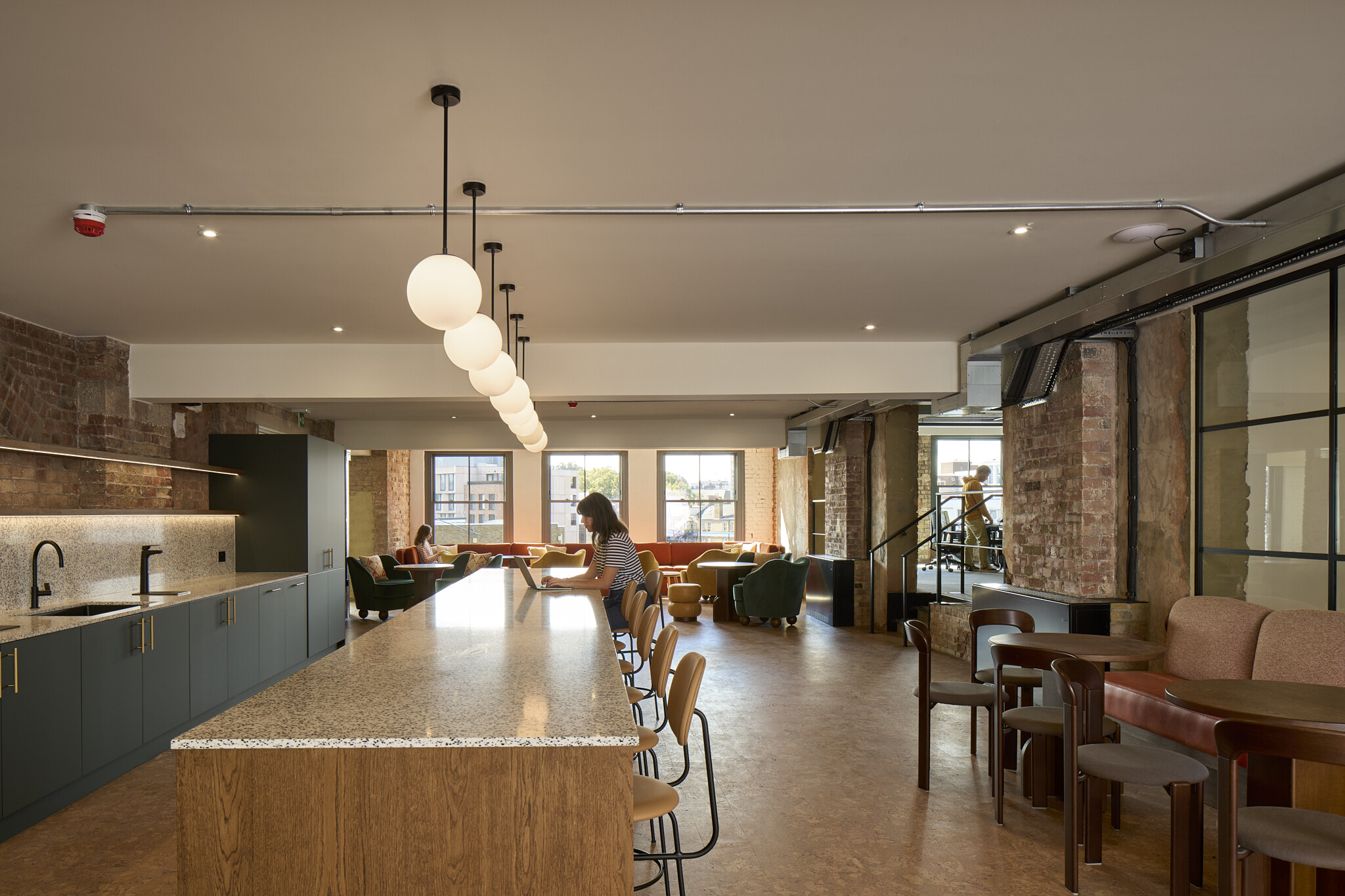 The Waterman teapoint and breakout area with terrazzo worktop, timber cabinetry and pendant lighting framed by exposed brick and soft seating