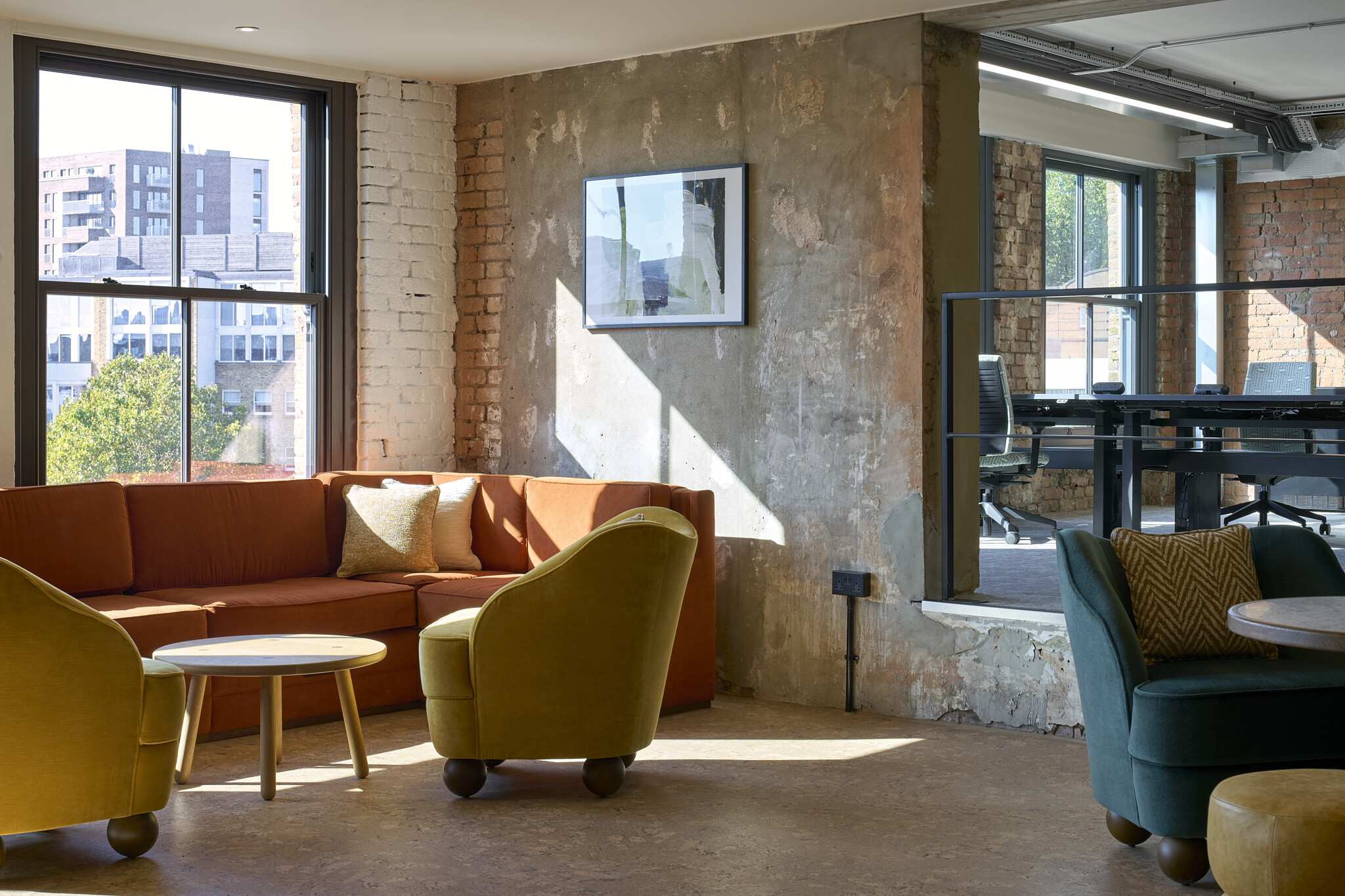 The Waterman social space with exposed brick, built-in banquette seating and colourful lounge chairs in a stripped-back industrial setting