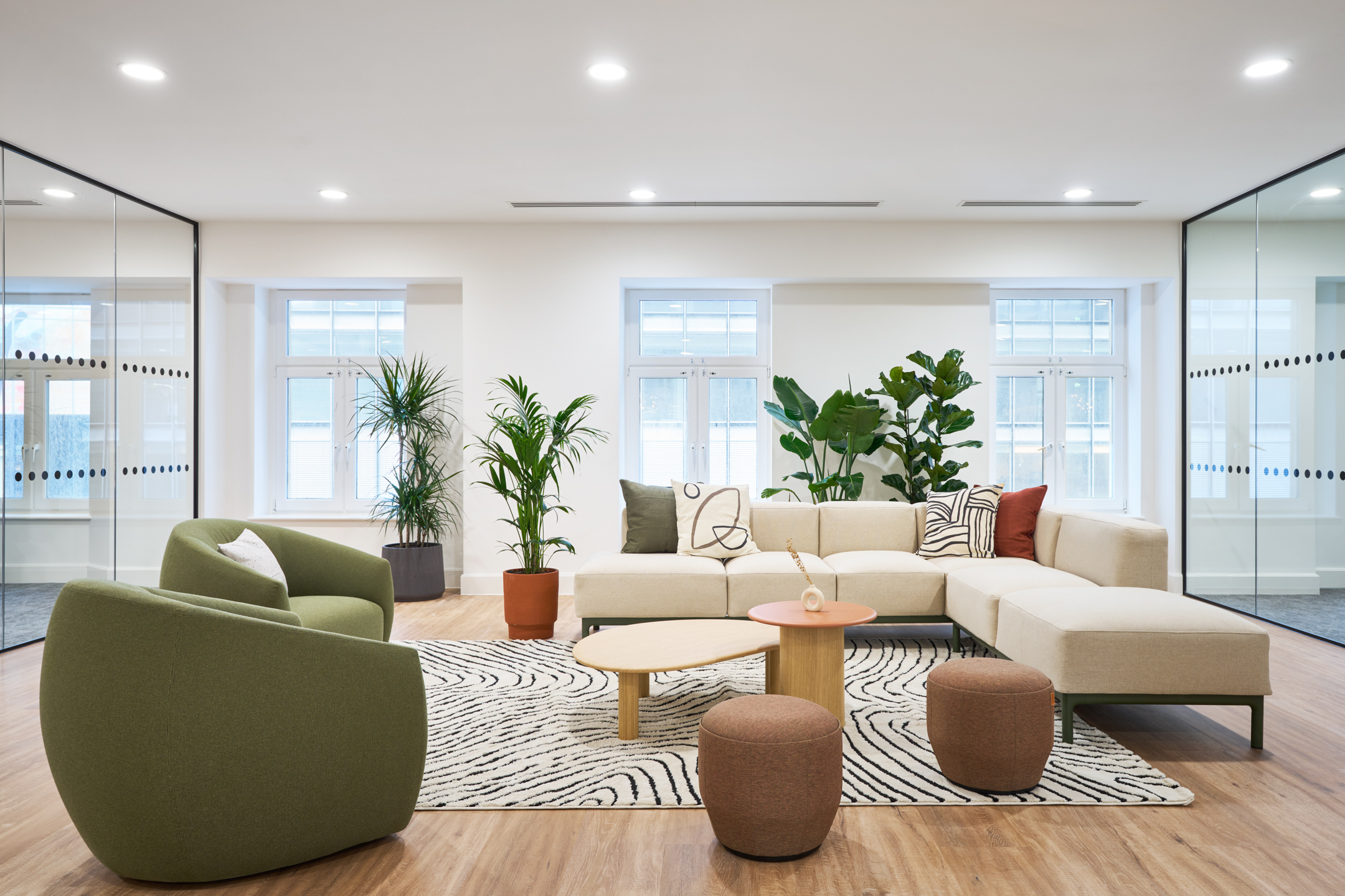 Modern breakout lounge at 7 Bishopsgate, Level 4, with contemporary furniture by Platfform for BGO, including a modular sofa and green armchairs.