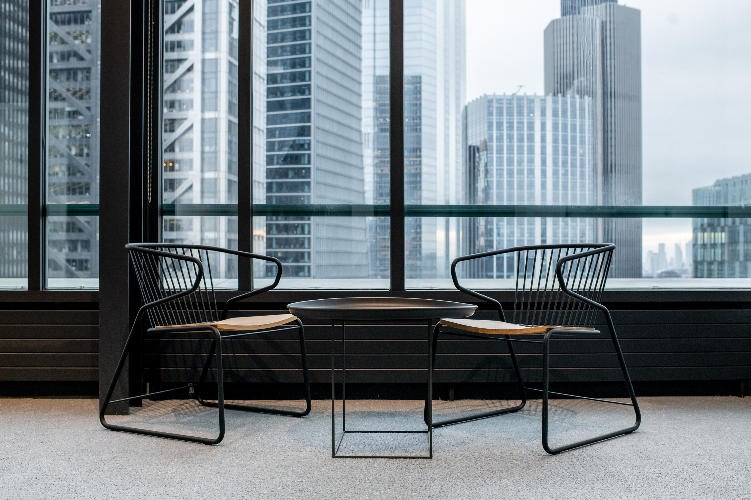 Minimalist lounge setting at 135 Bishopsgate with black wire-frame chairs and city views, curated by Platfform for British Land.