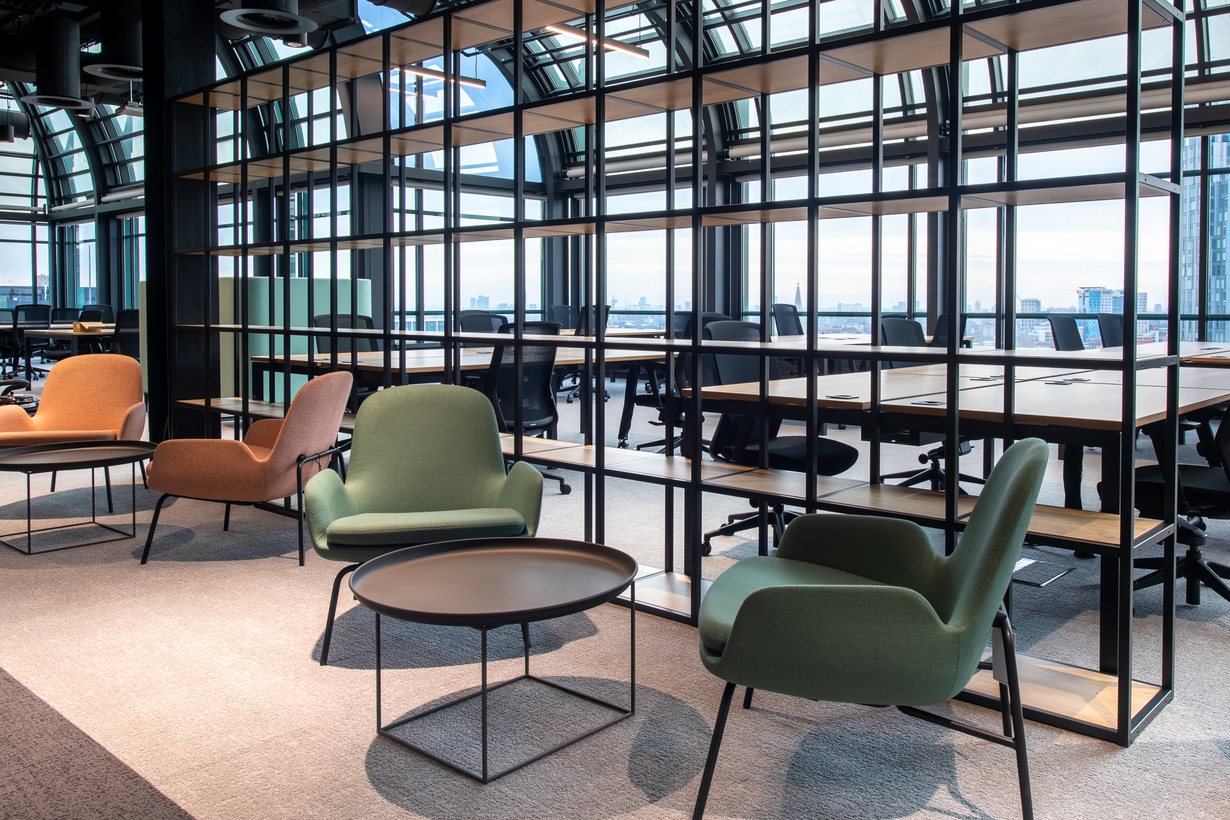 Lounge chairs and open shelving at 135 Bishopsgate, part of a flexible office layout furnished by Platfform for British Land under a curved glazed ceiling.