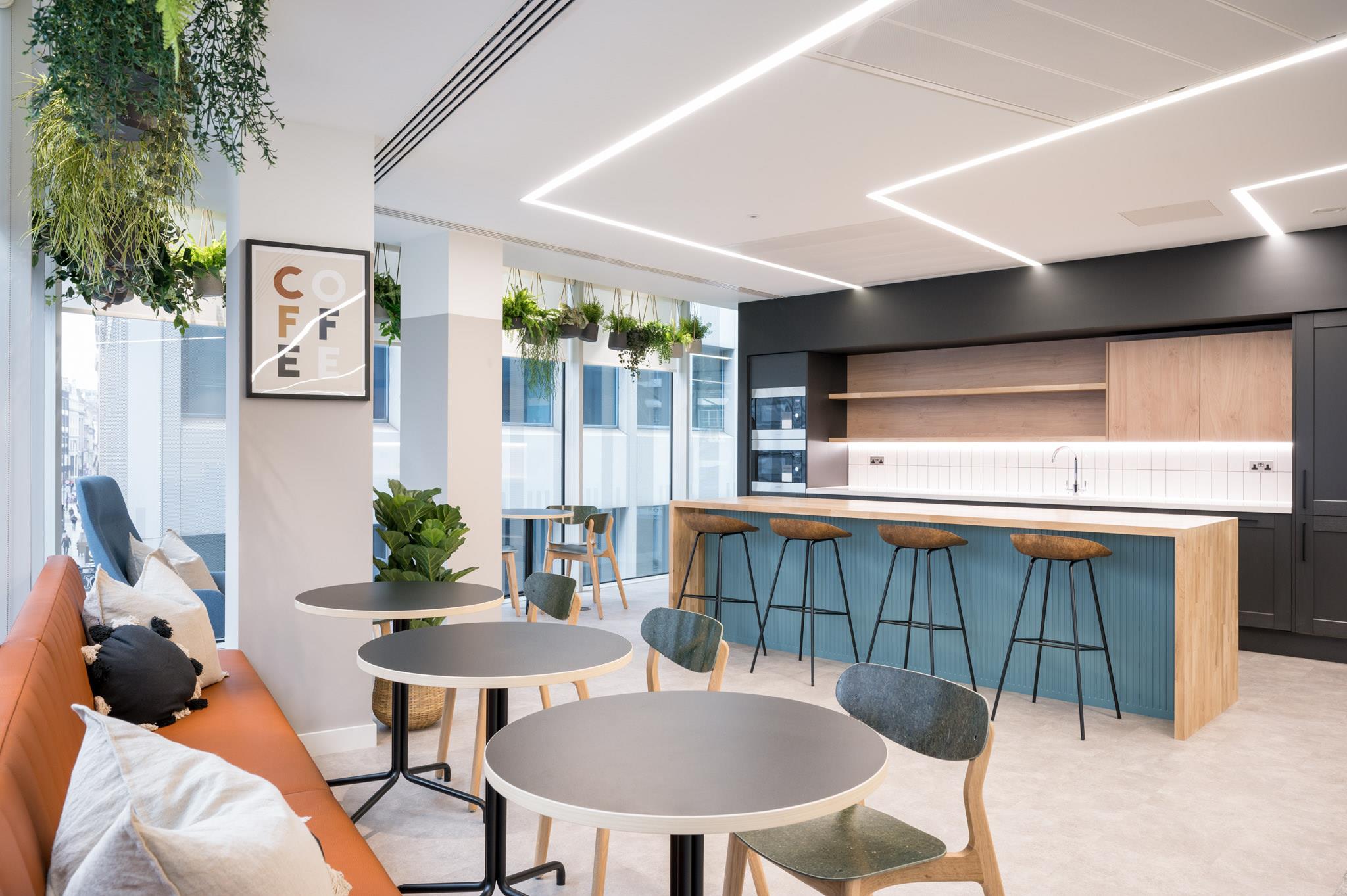 Teapoint at Platfform’s 70 New Oxford Street project, featuring a teal island with wood panelling, hanging plants, and mixed soft seating.
