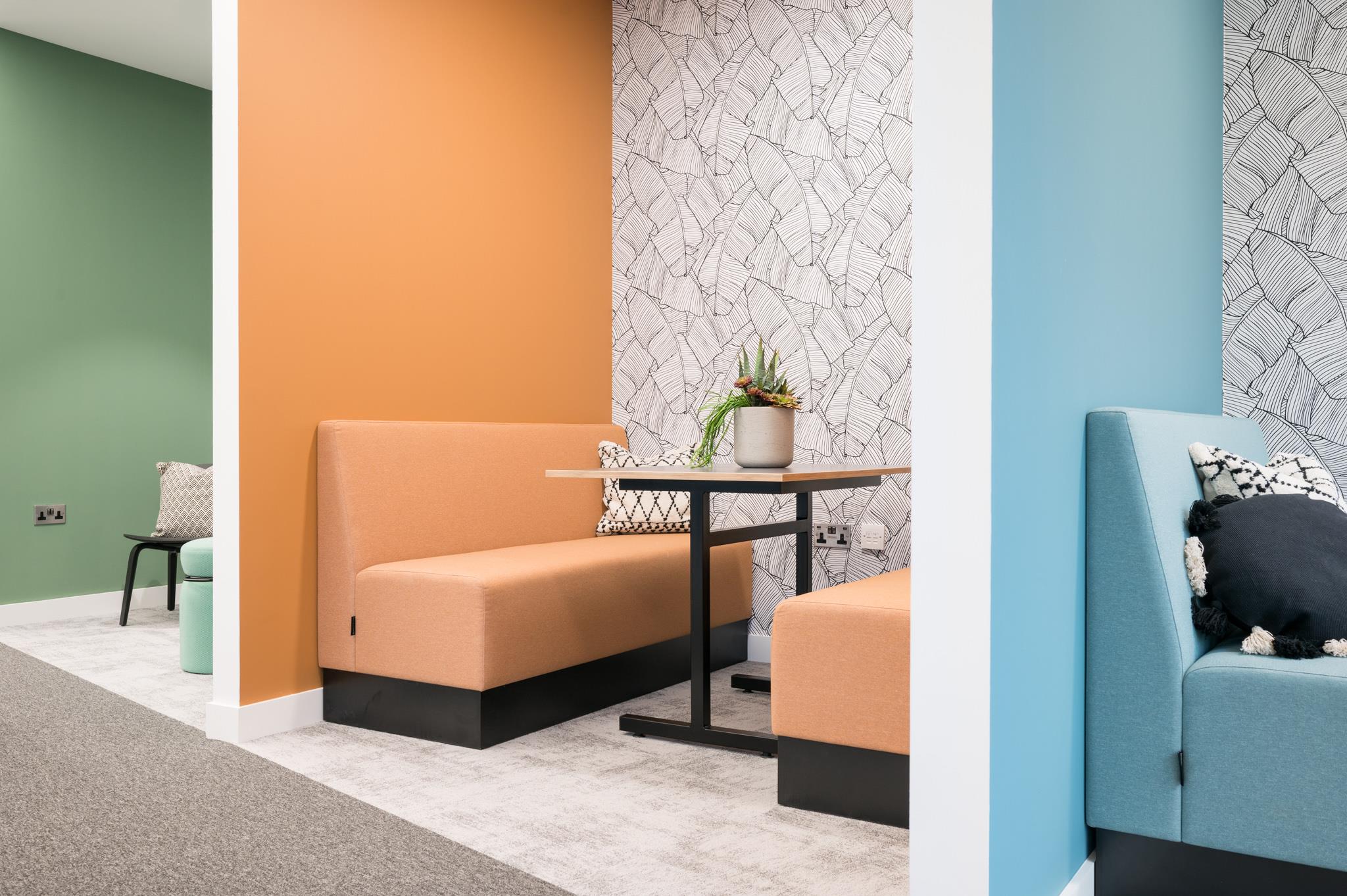 Soft seating and bold accent walls at Platfform's 70 New Oxford Street project, featuring peach and teal booths with patterned wallpaper for a vibrant, modern breakout space.