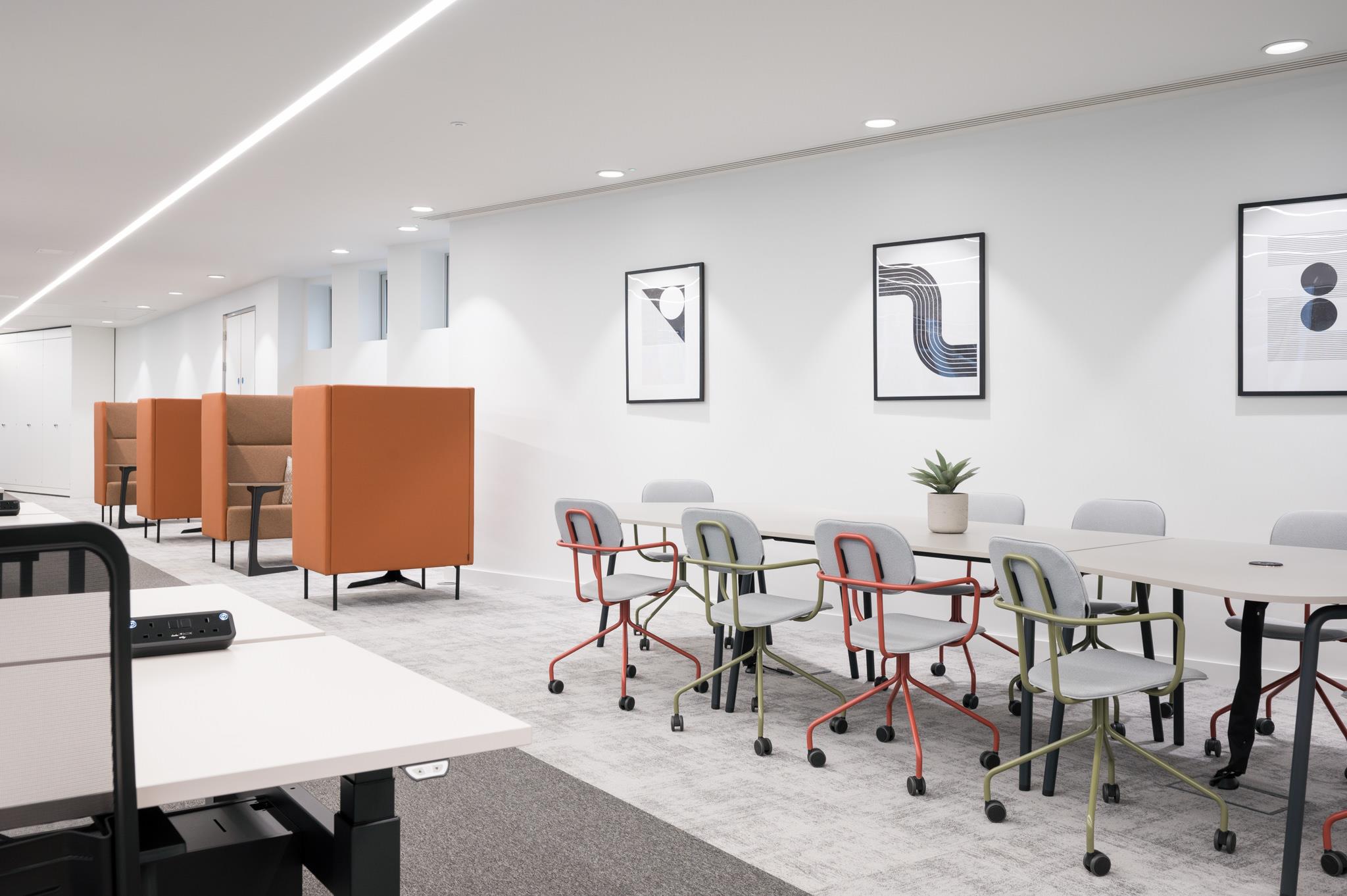 Flexible collaboration area at Platfform’s 70 New Oxford Street, combining high-back orange focus booths with a long shared table and playful task chairs.