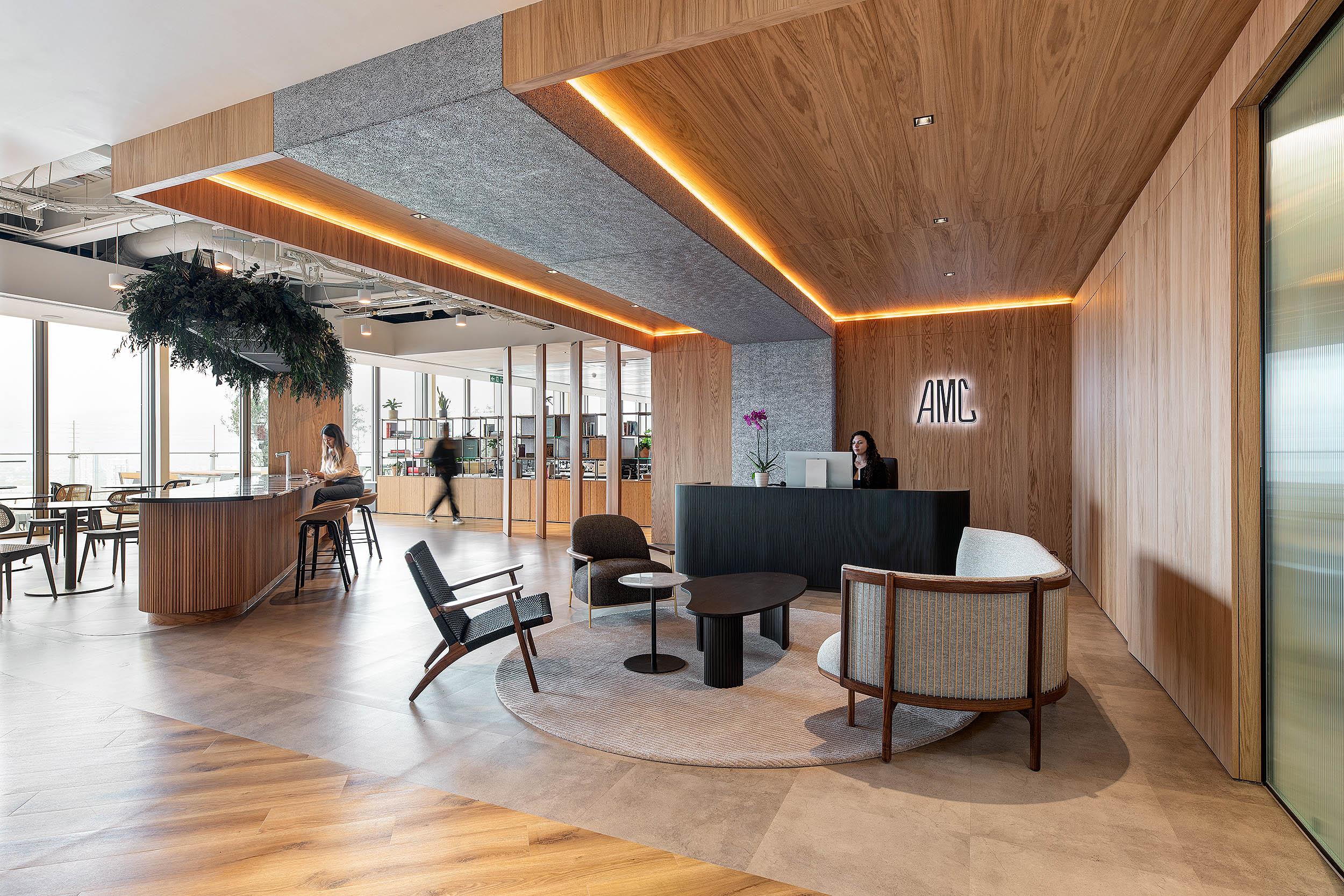 Reception and breakout area at AMC, furnished by Platfform with a warm mix of timber finishes, curved seating and lounge chairs.