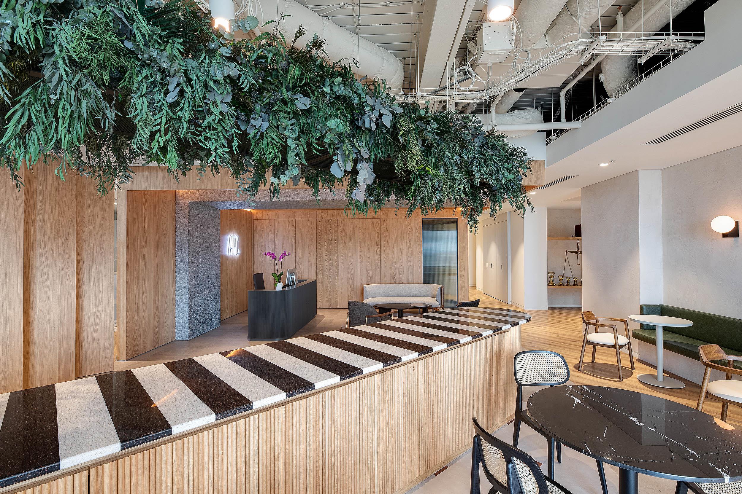 AMC’s reception and café space, styled with Platfform’s furniture including terrazzo bar counters, marble tables and mixed seating beneath a canopy of greenery.
