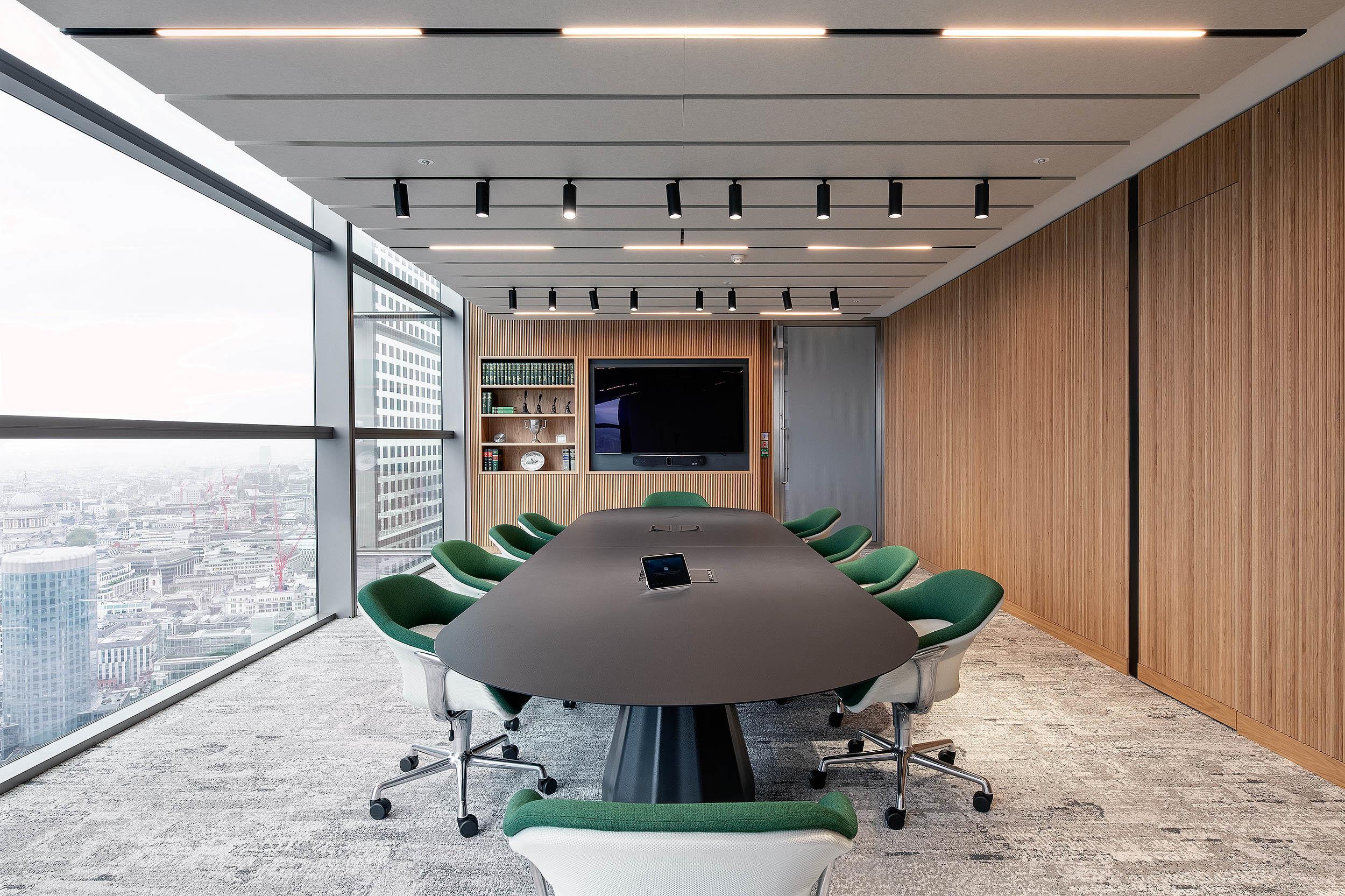 Boardroom at AMC furnished by Platfform, with green-accented ergonomic chairs and a matte black table set against full-height glazing and timber panelling.