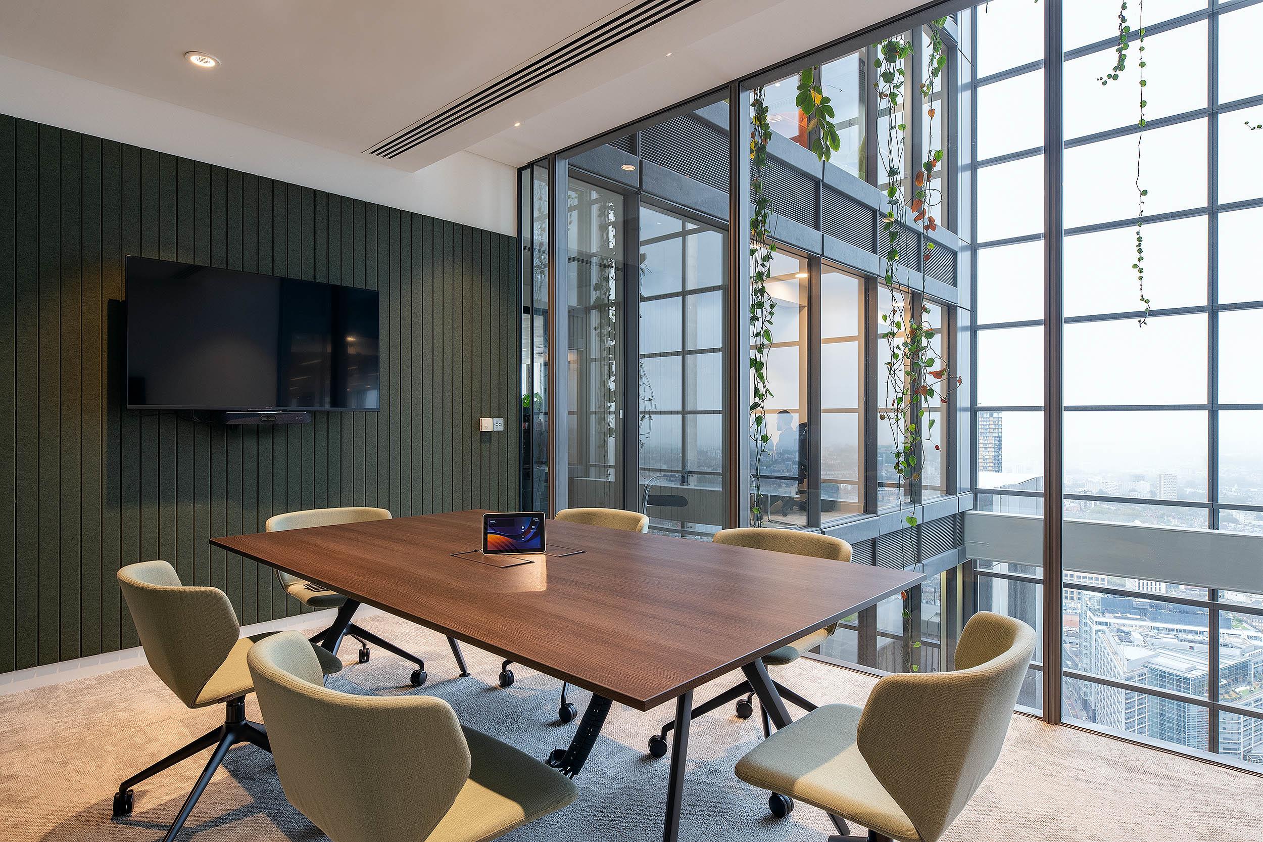 Meeting room at AMC featuring Platfform’s soft green task chairs and timber meeting table, set against panoramic views and acoustic wall panelling.