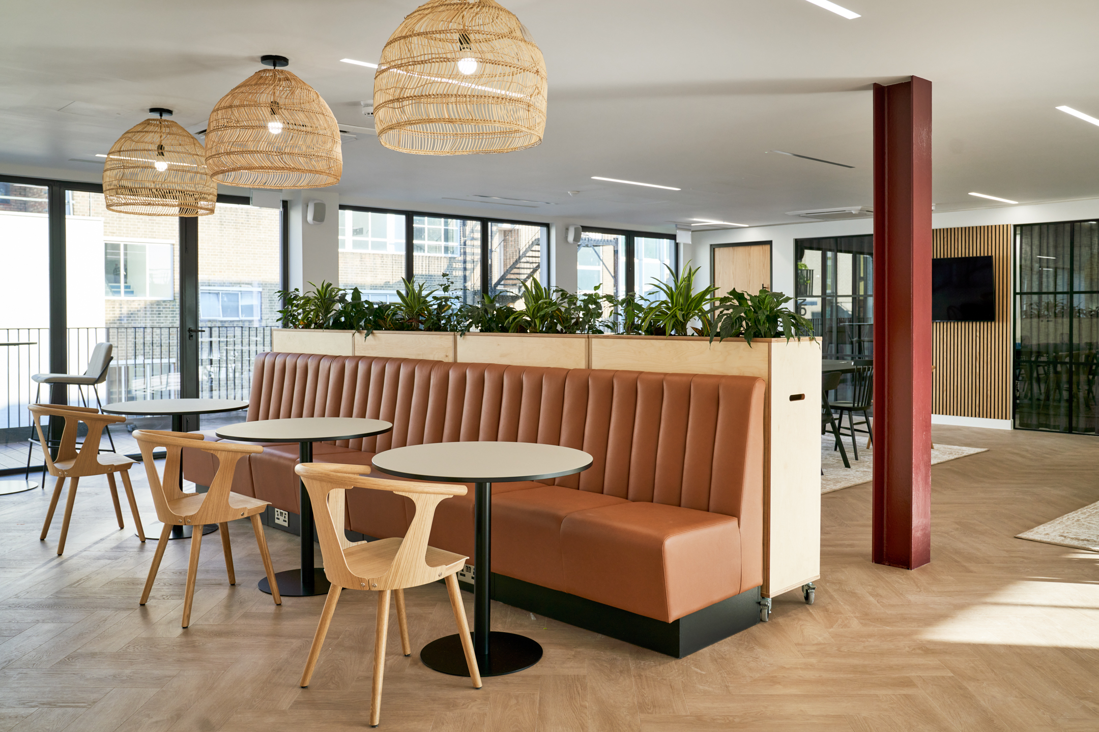 Café-style seating at Adyen with warm-toned banquettes, wooden chairs, and woven pendant lighting, all thoughtfully curated and delivered by Platfform.