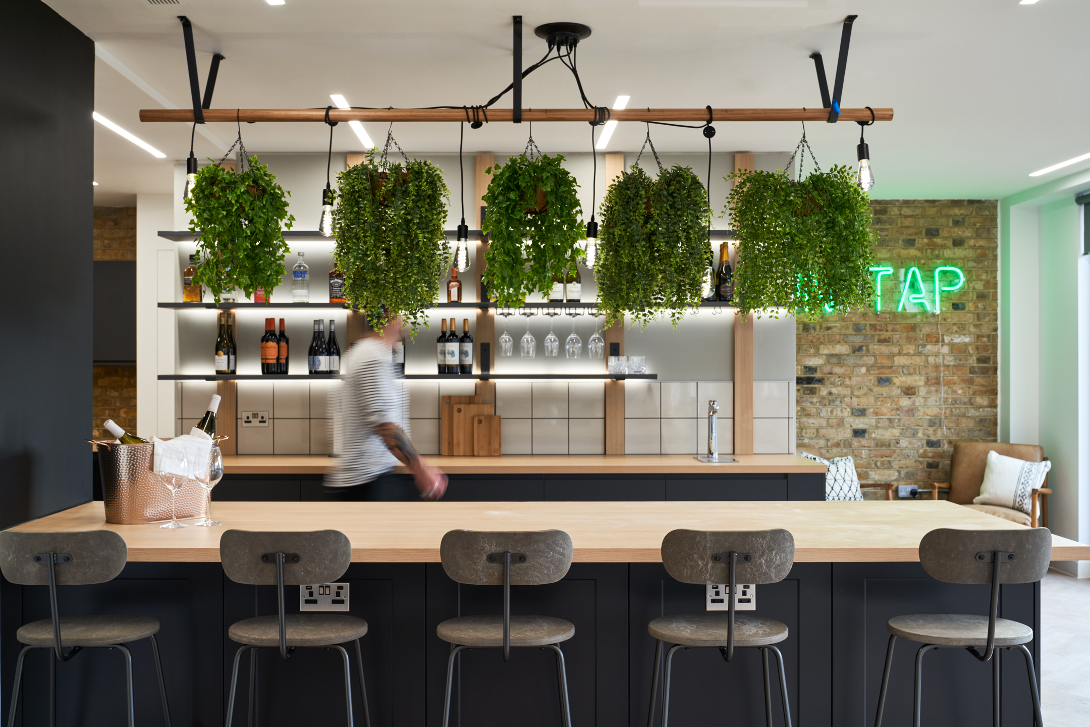 Teapoint bar in Adyen’s office with high stools, suspended greenery and a custom shelving unit, furnished and styled in collaboration with Platfform.