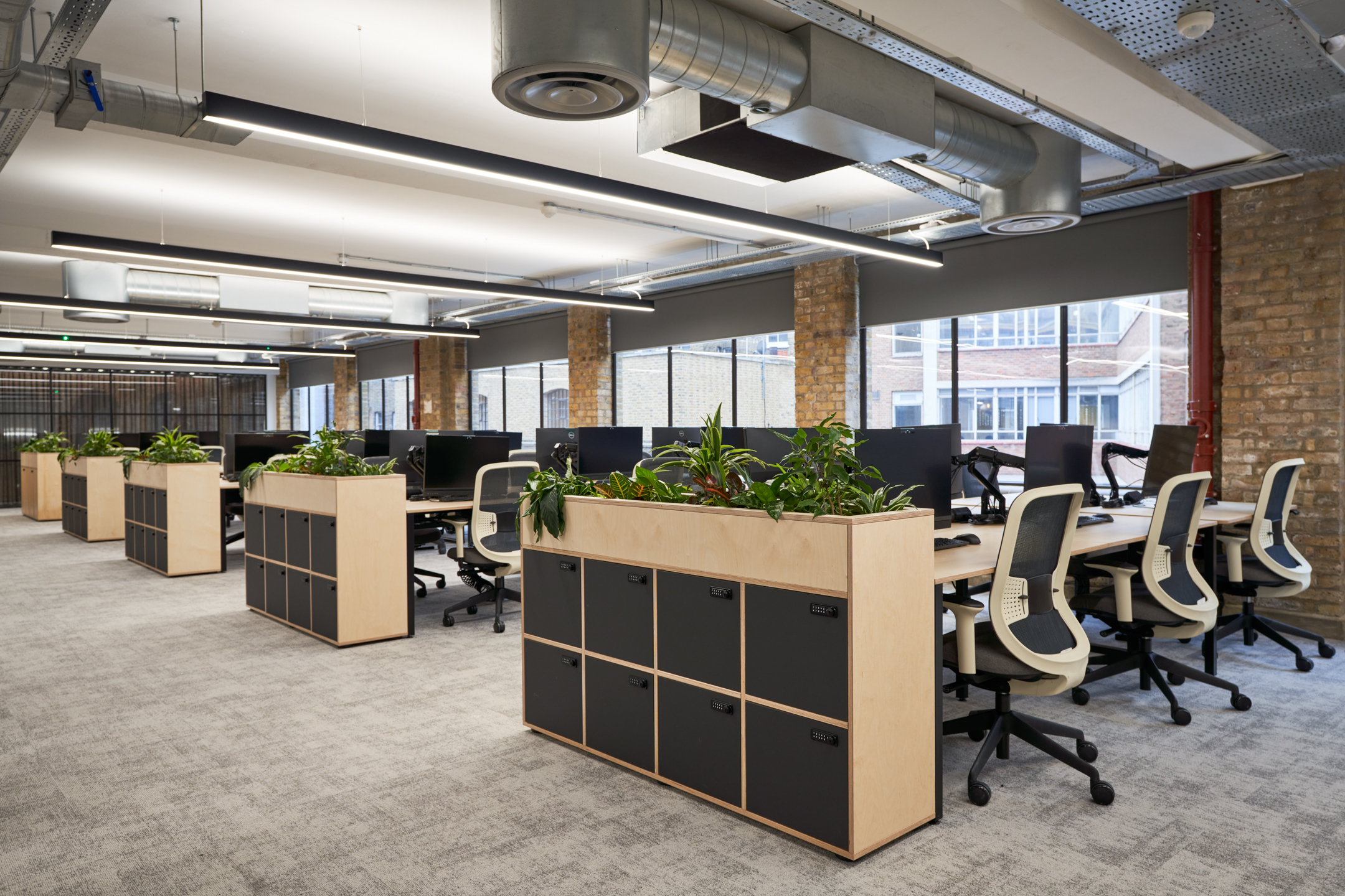 Workspace at Adyen with sit-stand desks, mesh-back chairs, and locker planters supplied through Platfform to balance functionality and greenery.