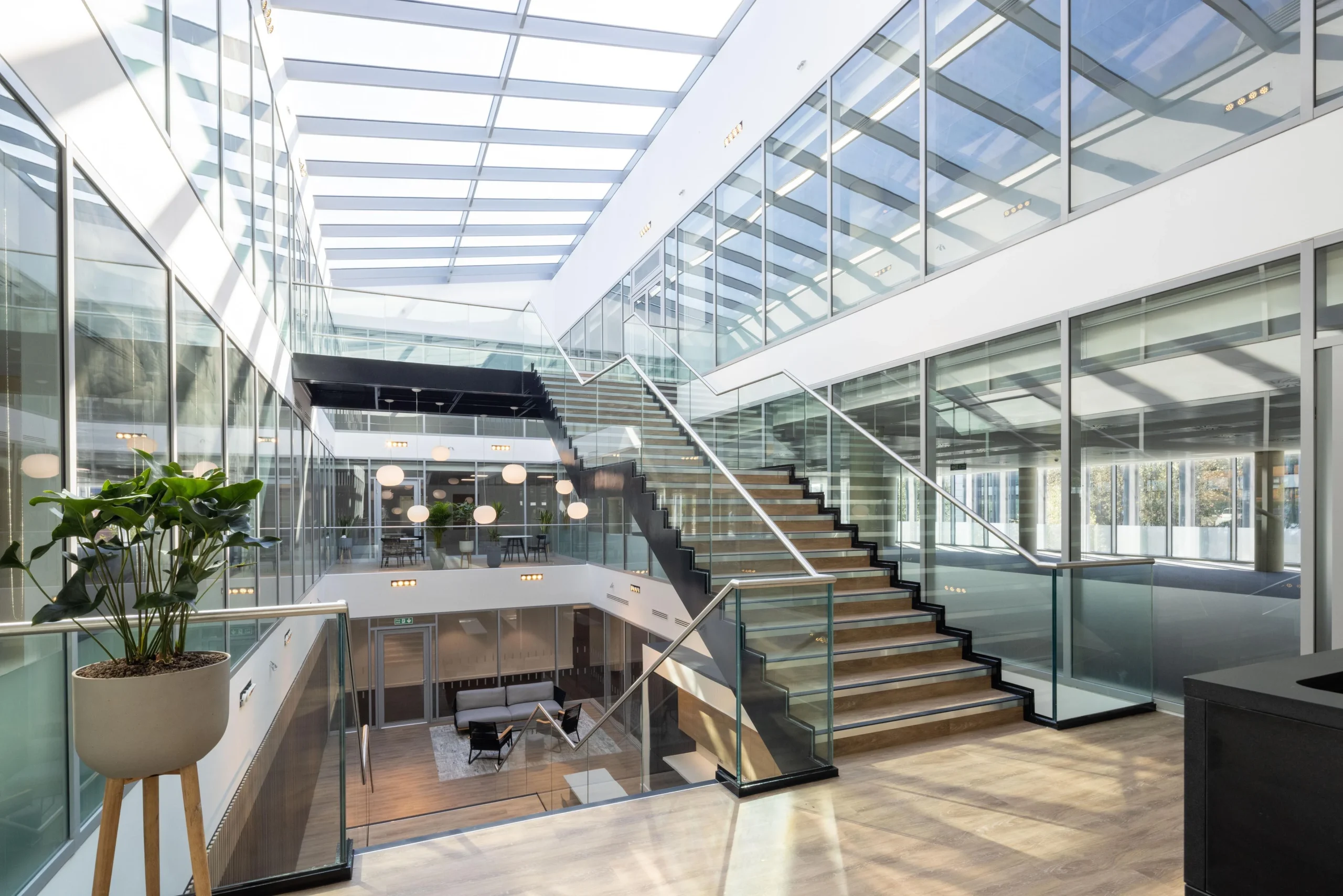Central staircase at The Dock designed for Alchemy Asset Management, with natural light flooding the atrium and stylish furnishings by Platfform visible across all levels.