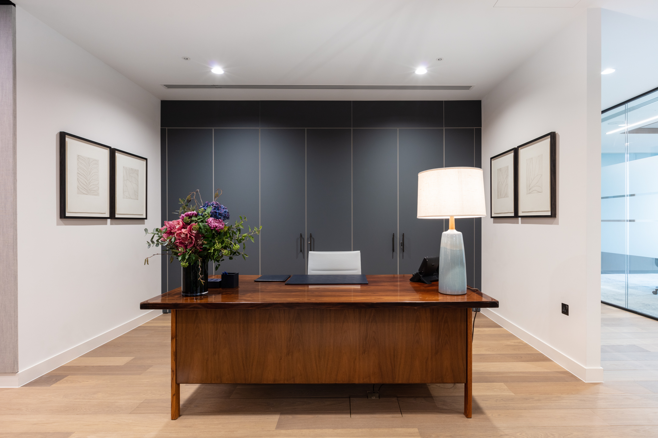 Reception desk for an Asset Management Firm with bold joinery and styling by Platfform including a statement lamp and floral arrangement.