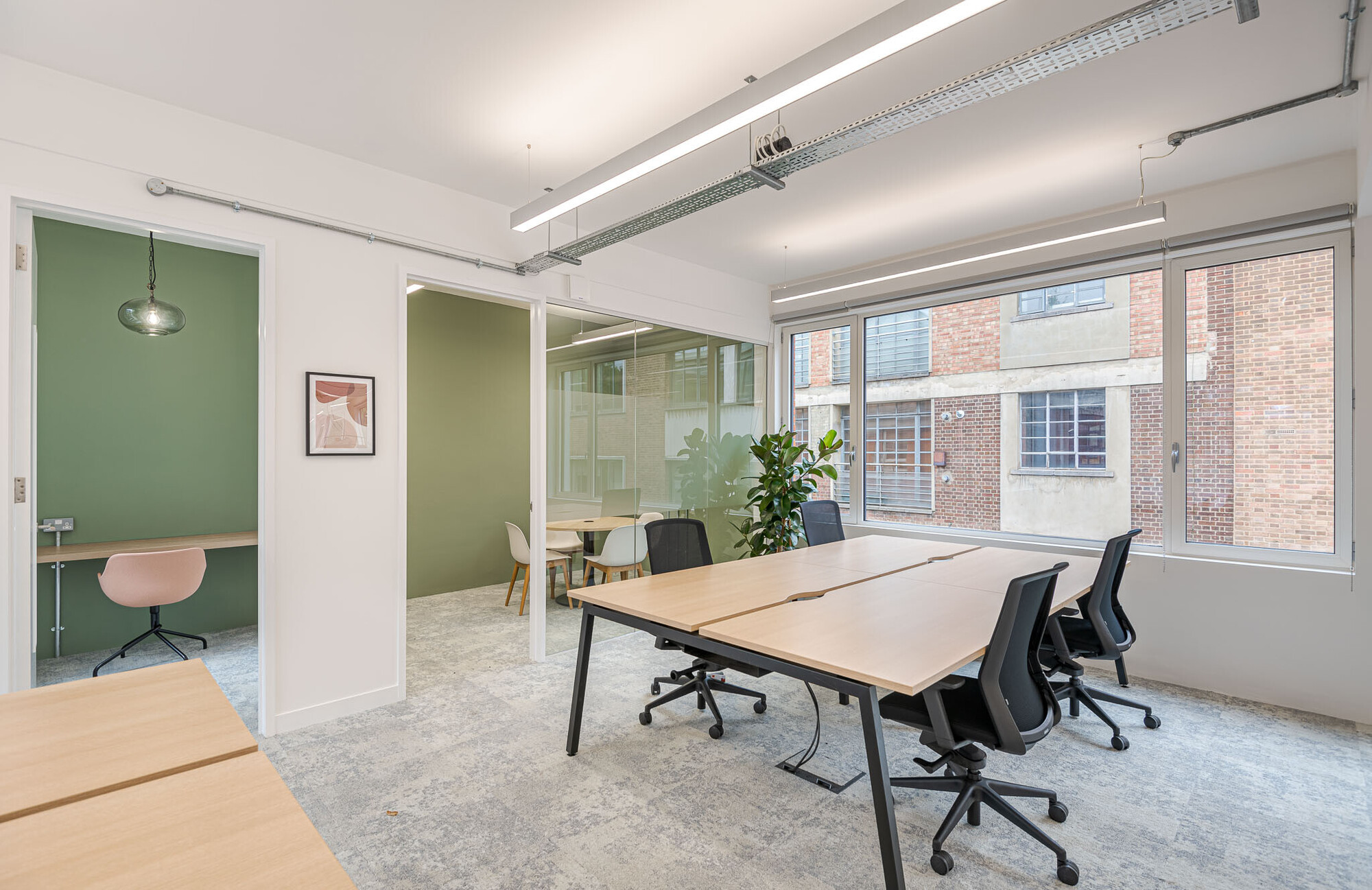 Minimalist office breakout space on Berry Street designed by Platfform, with sleek chairs and a view of the green outdoors.