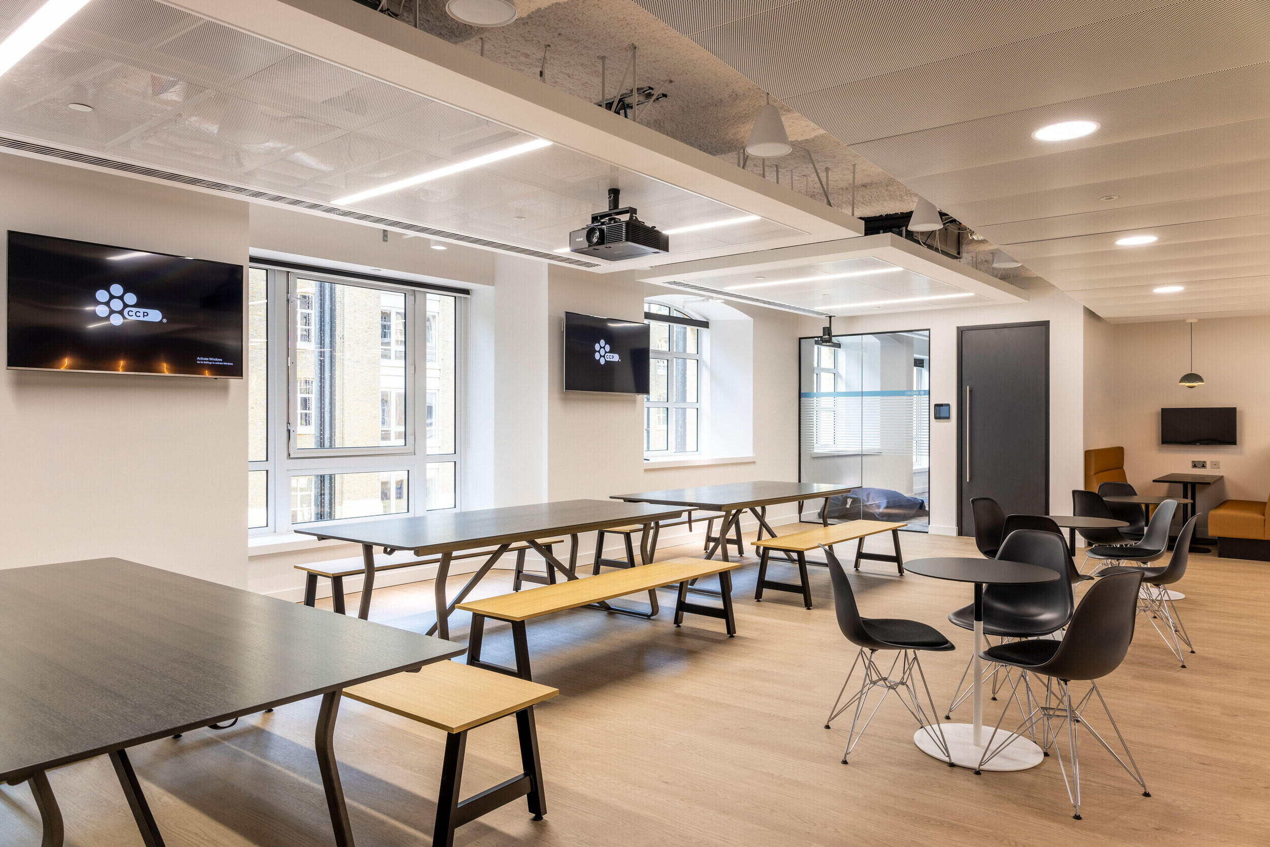 Collaborative communal area in CCP Games' office with furniture by Platfform. Long wooden benches and tables, modern lighting, and open-plan design.