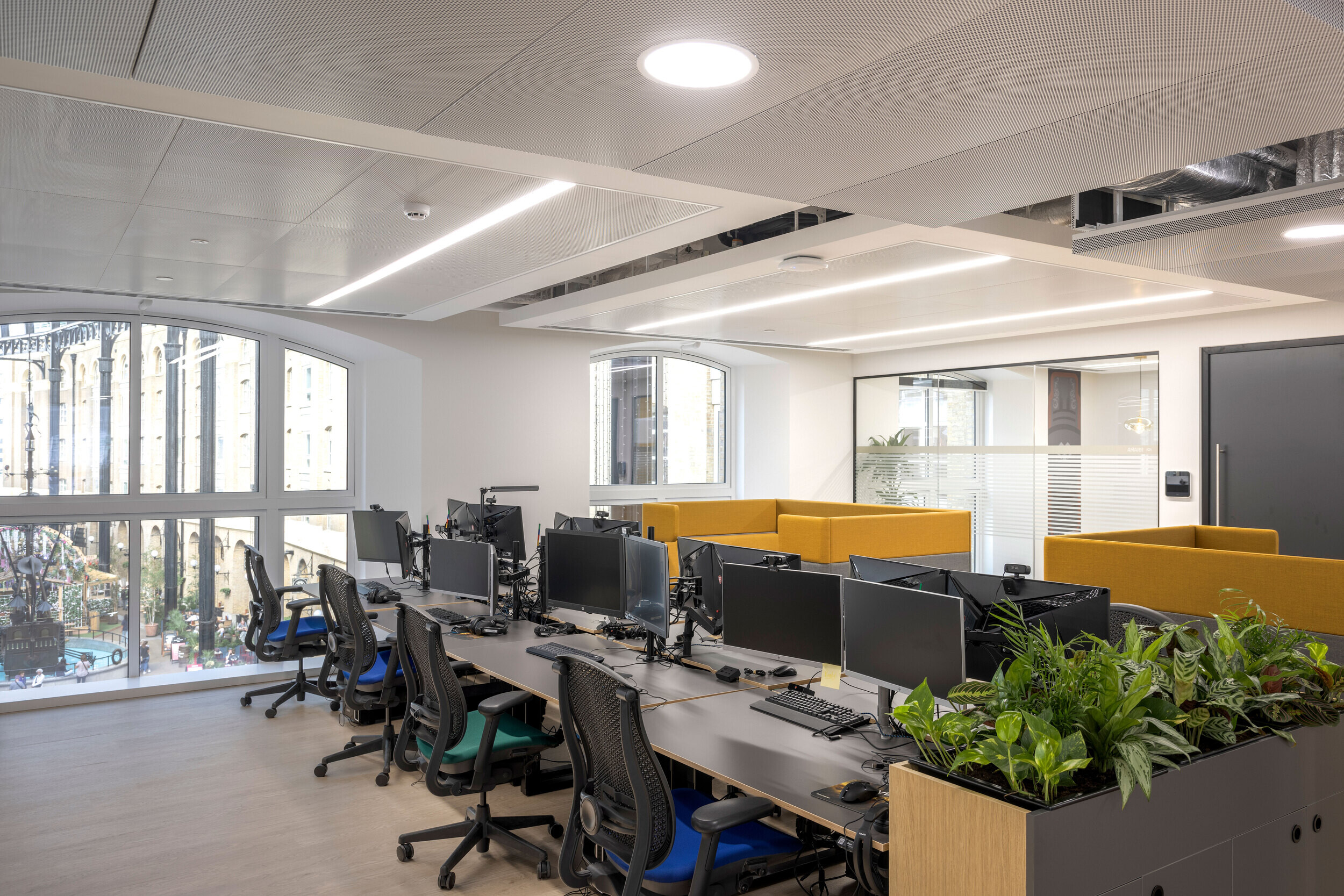 Bright workstations in CCP Games’ office, furniture by Platfform, with large windows overlooking London’s iconic Hay’s Galleria.