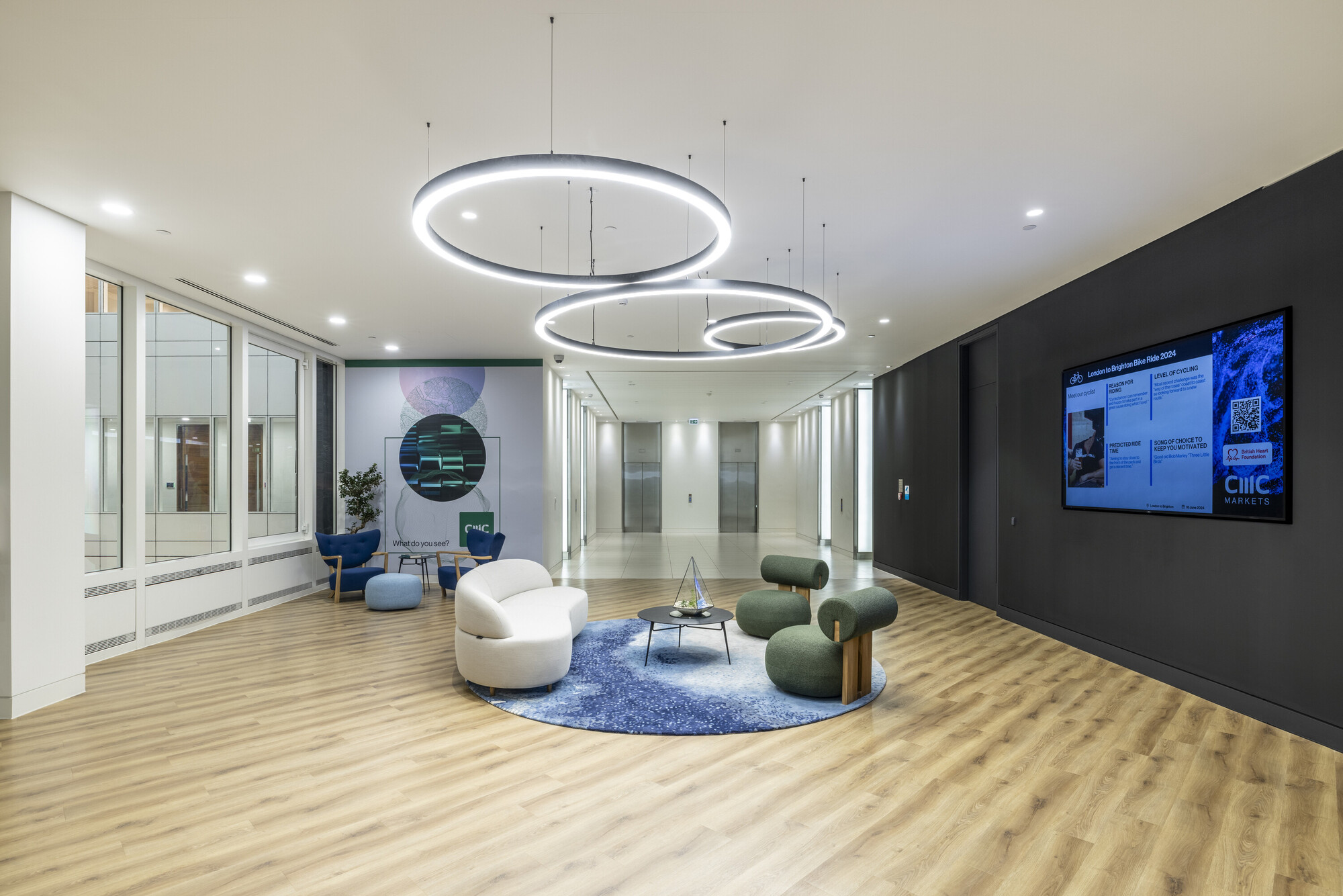 Modern breakout area at CMC Markets' HQ designed by Platfform, featuring circular LED lighting, contemporary seating, and wood-effect flooring
