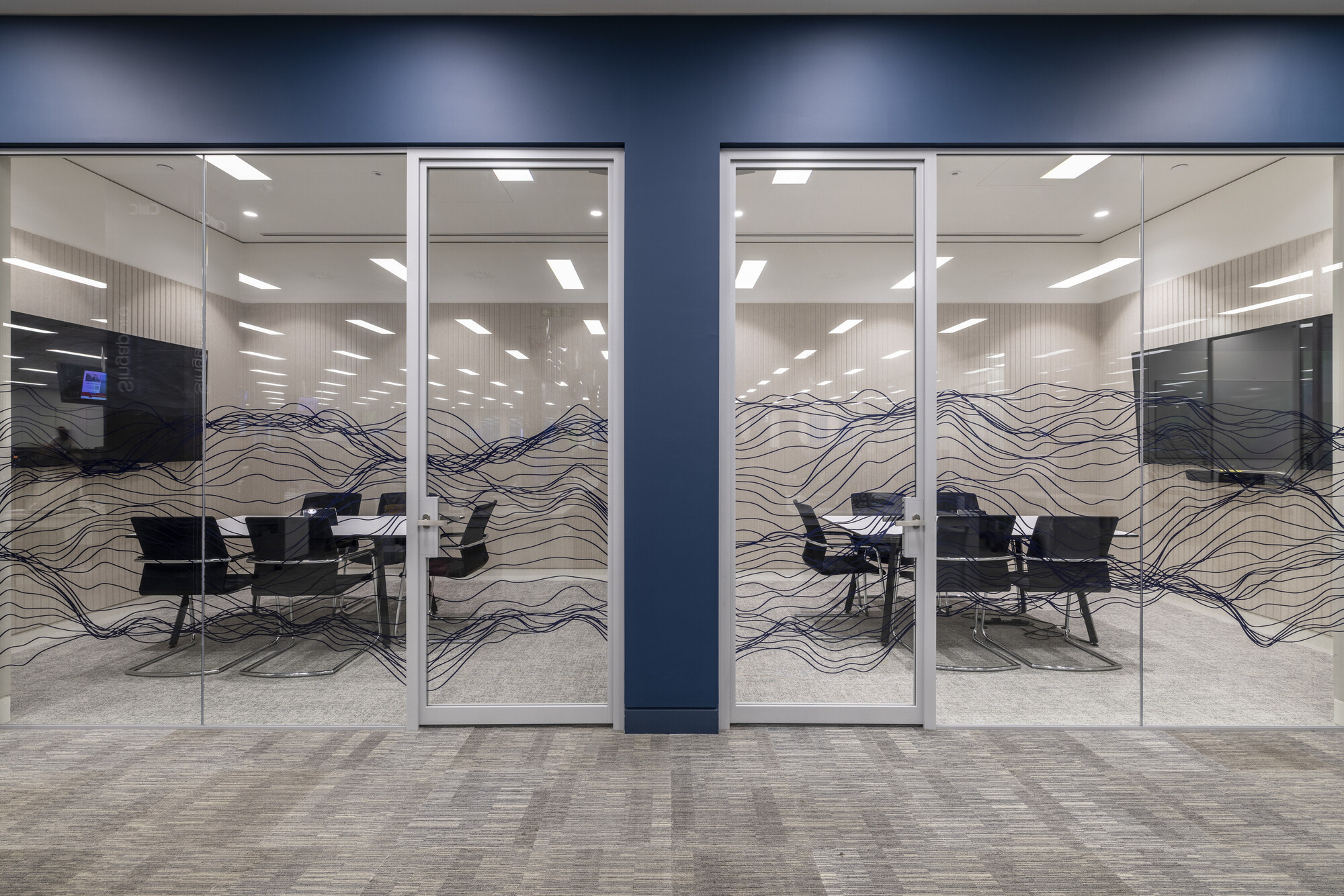 Dual meeting rooms at CMC Markets’ Whitechapel office designed by Platfform, featuring custom wave-patterned glazing for added privacy and aesthetic appeal.