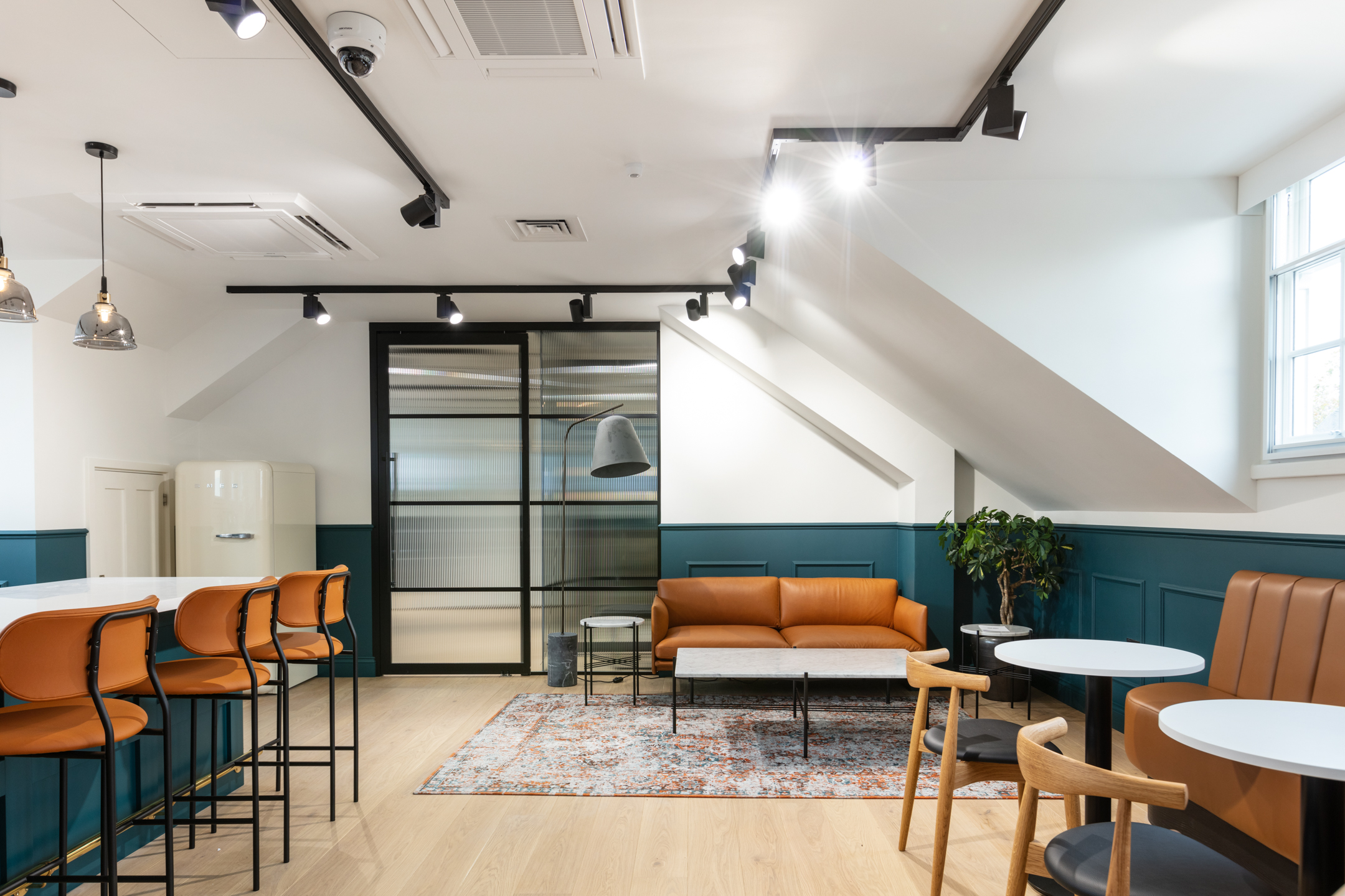 Cain International breakout space with layered furniture consultancy by Platfform, including tan banquette seating, soft lounge chairs and café-style tables.