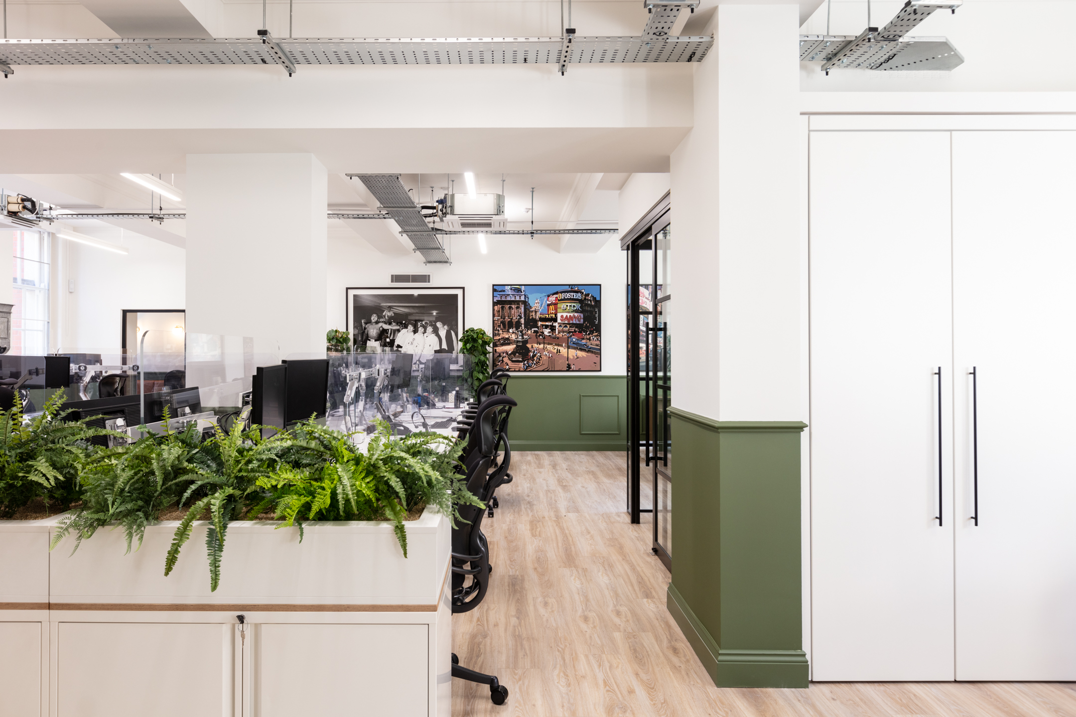 Open-plan office at Cain International with ergonomic task chairs, storage-integrated planting and custom desks, all sourced through Platfform as furniture consultant.