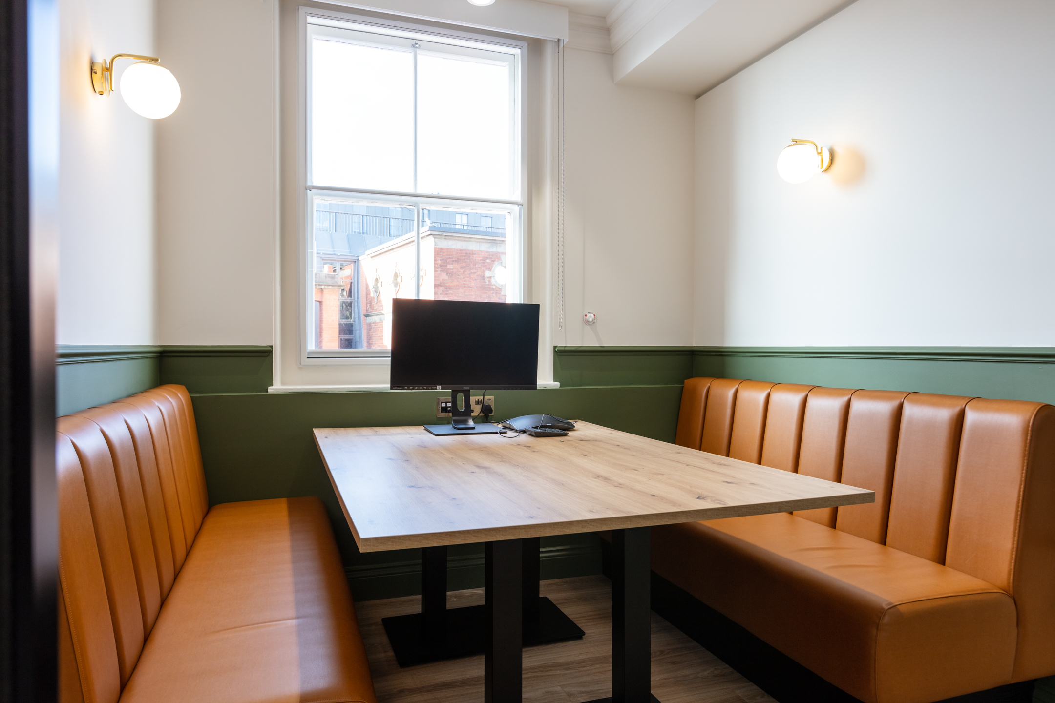Meeting booth at Cain International with built-in tan banquette seating and integrated screen, with all furniture supplied and specified by Platfform.