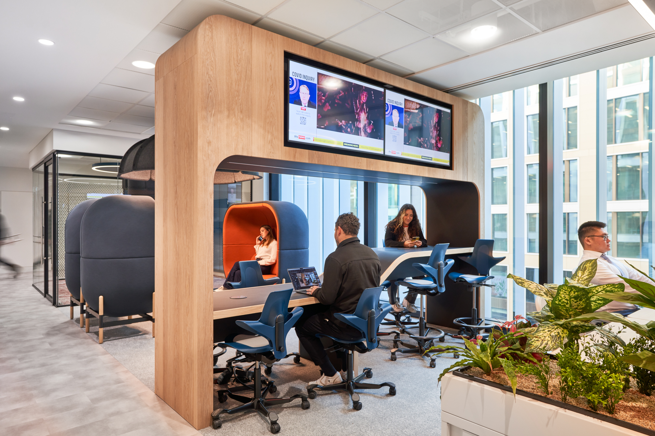 High table collaboration zone at capital.com with integrated screens, ergonomic stools and acoustic work booths installed by Platfform.