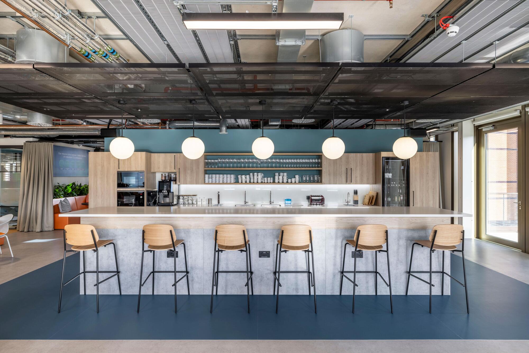 Carbon Clean’s teapoint area with timber bar stools and integrated storage, furnished by Platfform to support social connection and breakout use.