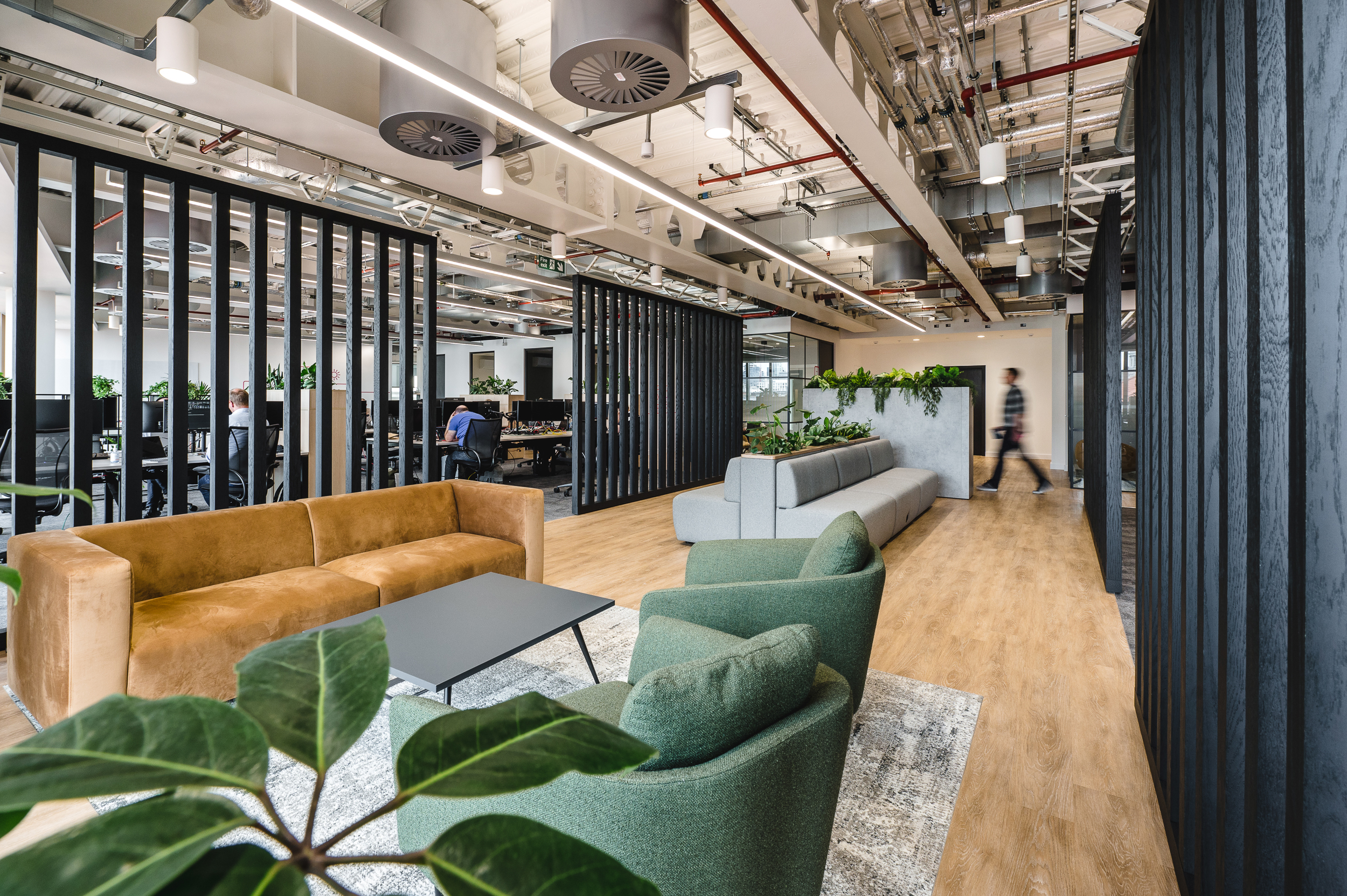 Breakout and workspace at Everyone TV featuring bespoke furniture consultancy pieces, including a tan velvet sofa, green armchairs, and soft grey modular seating.