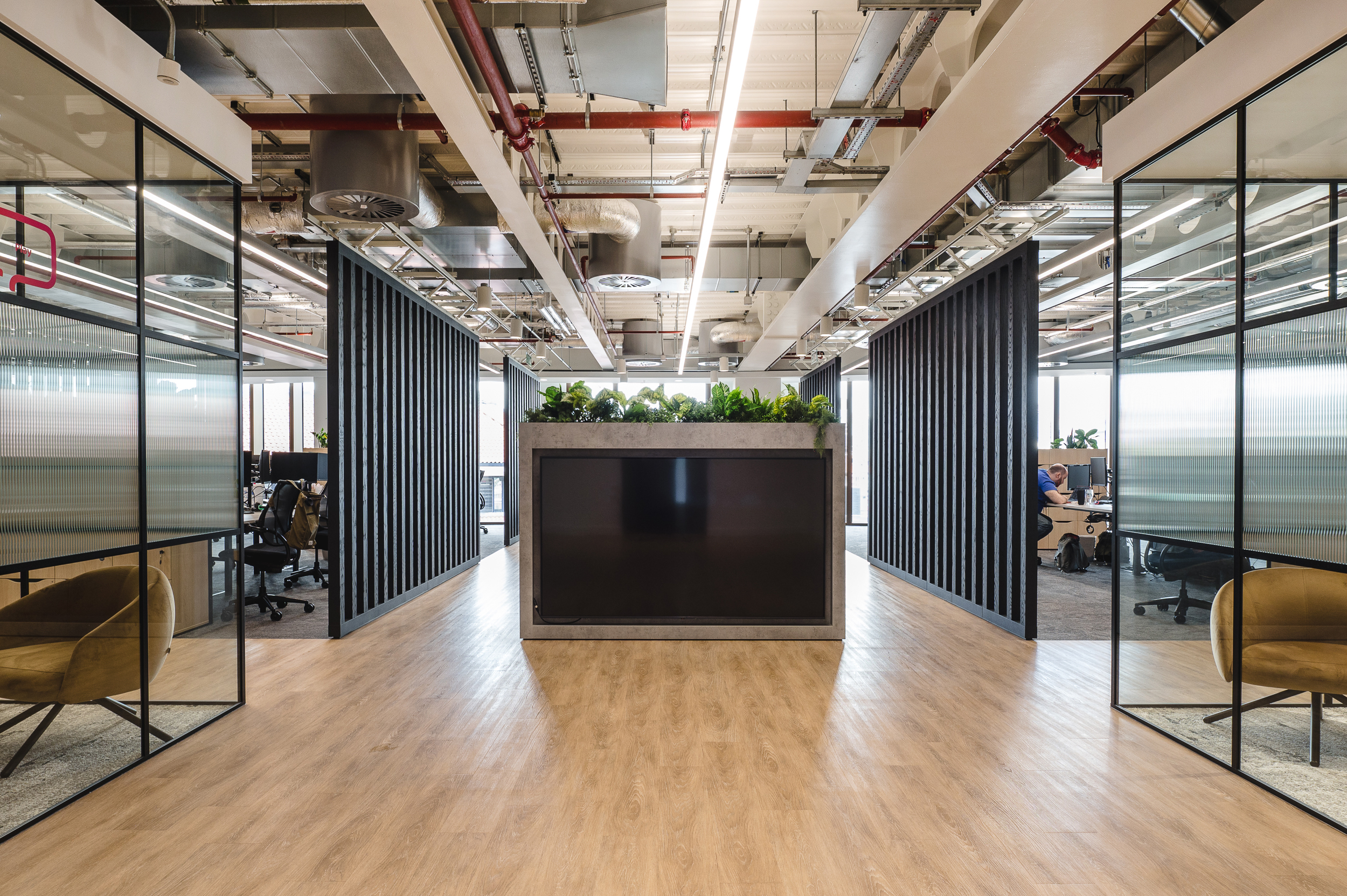 Entry area at Everyone TV with bespoke furniture consultancy pieces, including velvet lounge chairs and ergonomic desk seating within glazed meeting rooms.