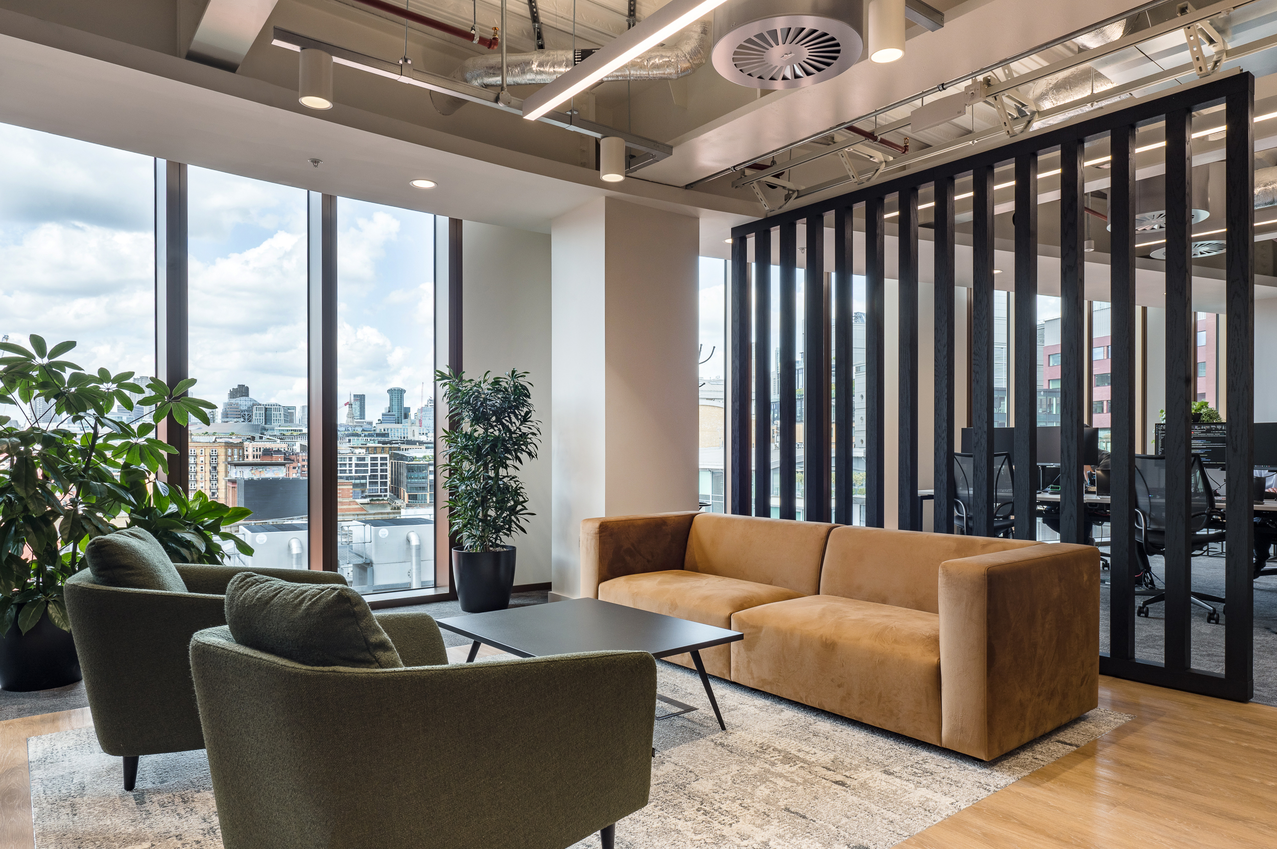 Relaxed meeting zone at Everyone TV, complete with a tan velvet sofa, green armchairs and soft furnishings.