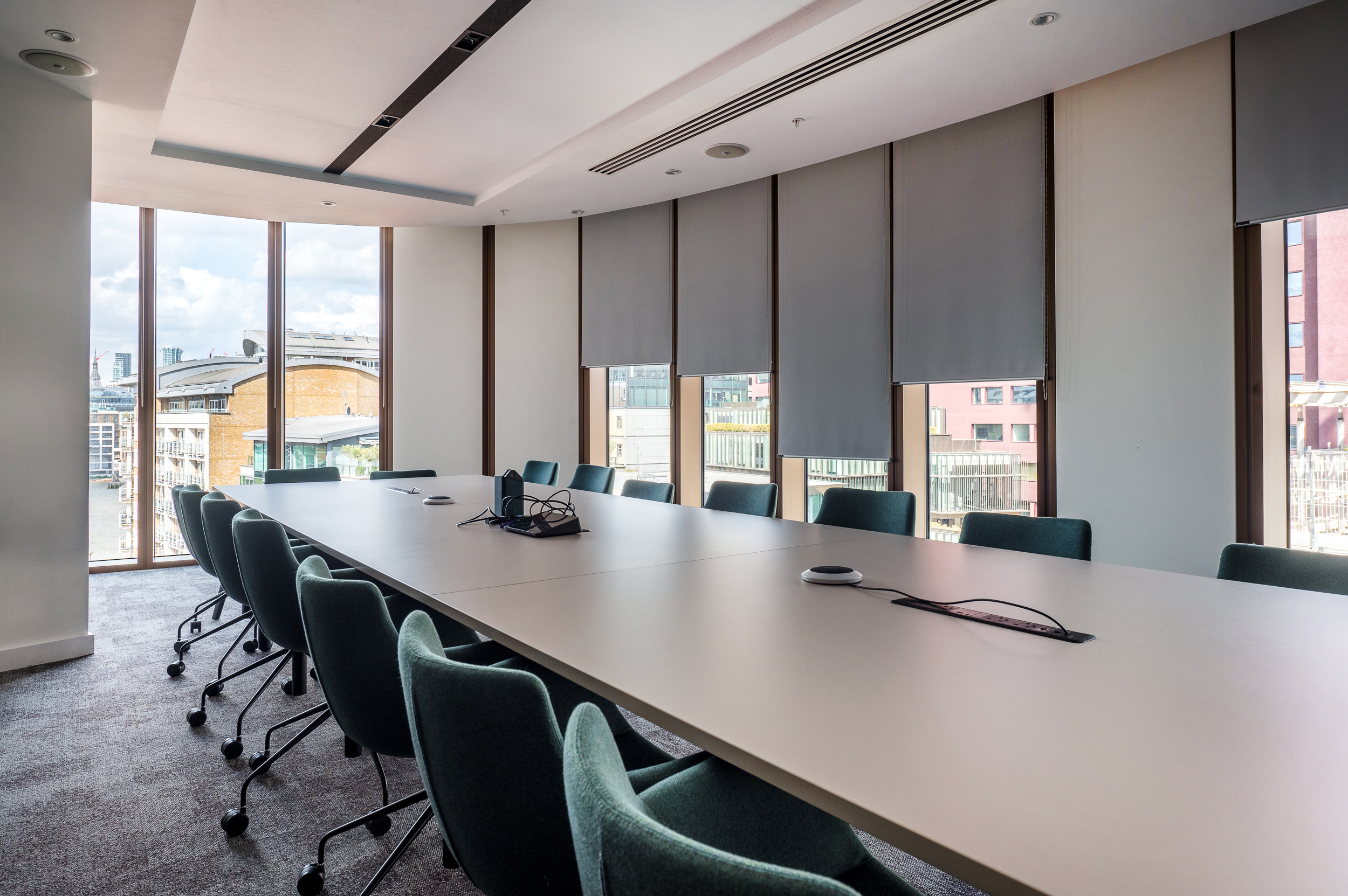 Boardroom at Everyone TV with a long meeting table and fully upholstered green chairs on castors.