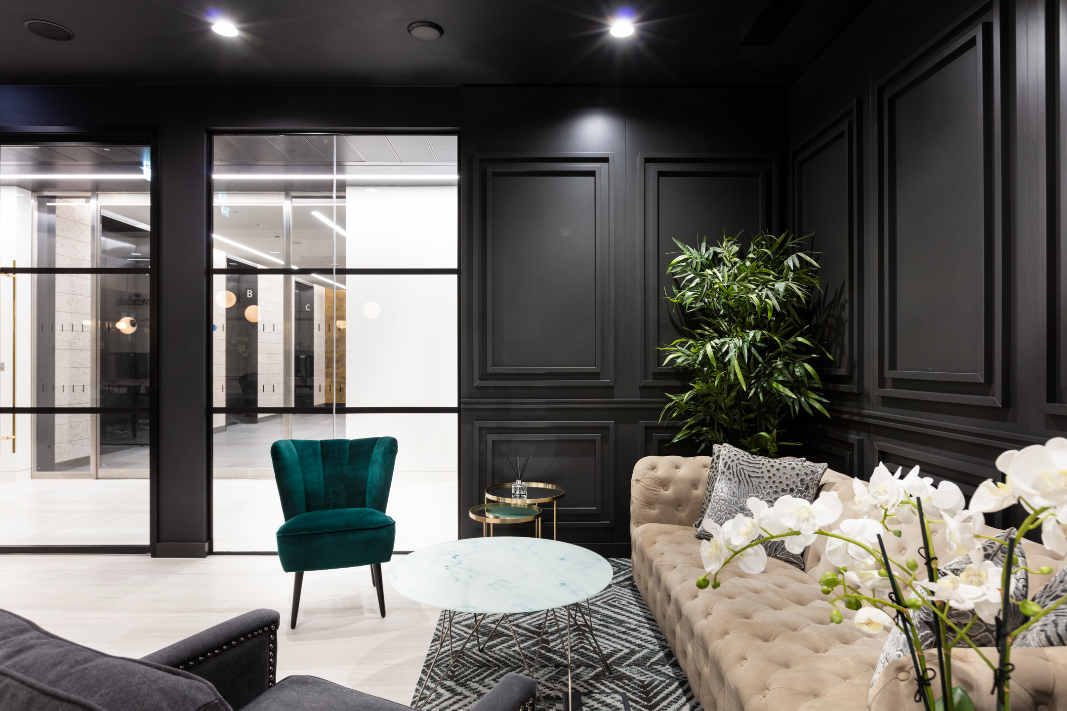 finnCap lounge area with statement furniture by Platfform, including a velvet armchair, buttoned sofa and marble-topped table in a dark-panelled setting.