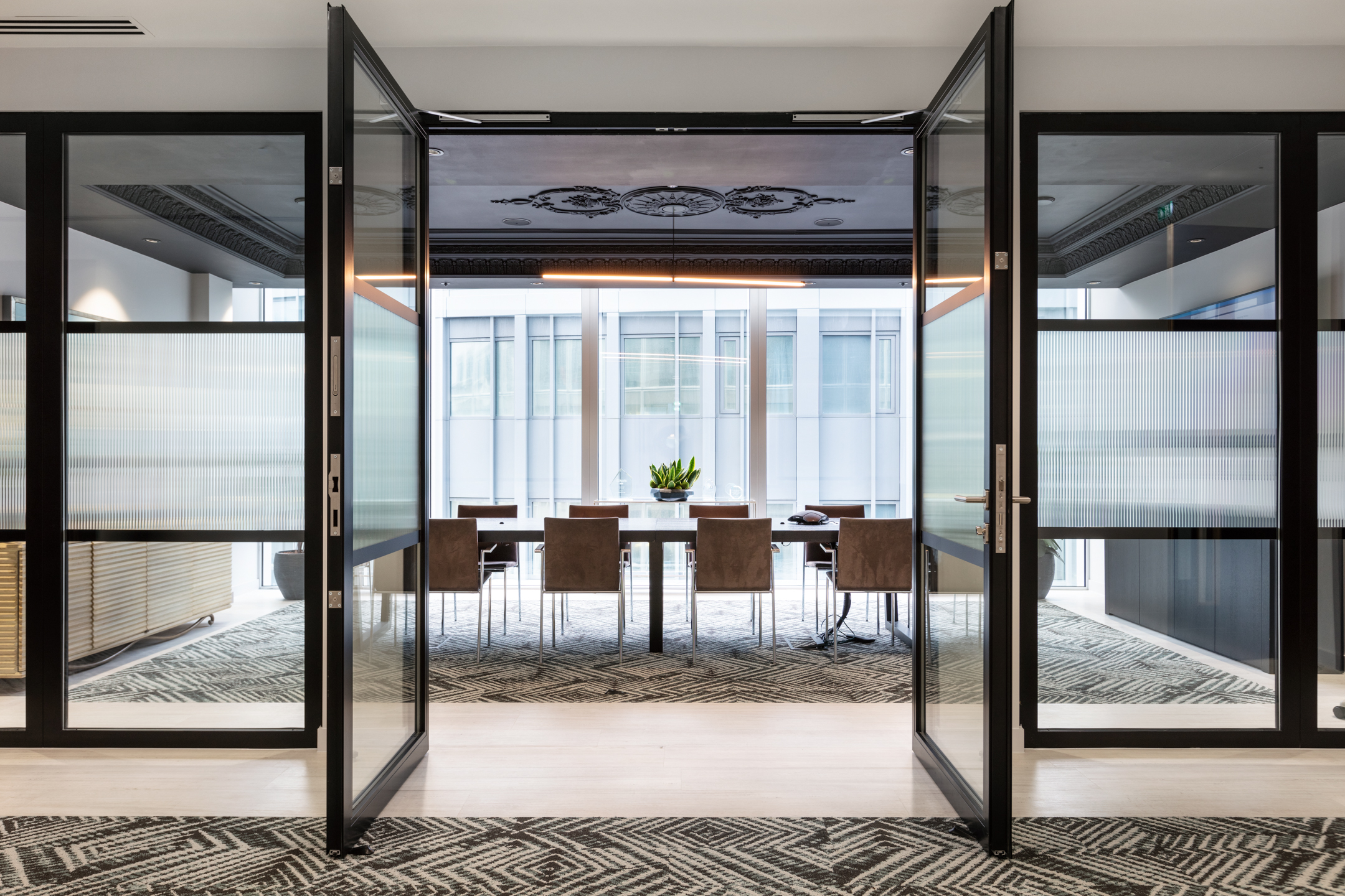 Entrance to the finnCap boardroom with furniture by Platfform, including a central meeting table and suede chairs framed by glazed double doors.