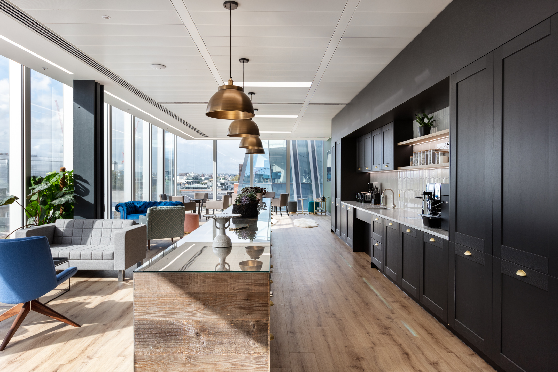finnCap teapoint and breakout area with mixed lounge furniture by Platfform, featuring a timber kitchen, brass lighting and city views.