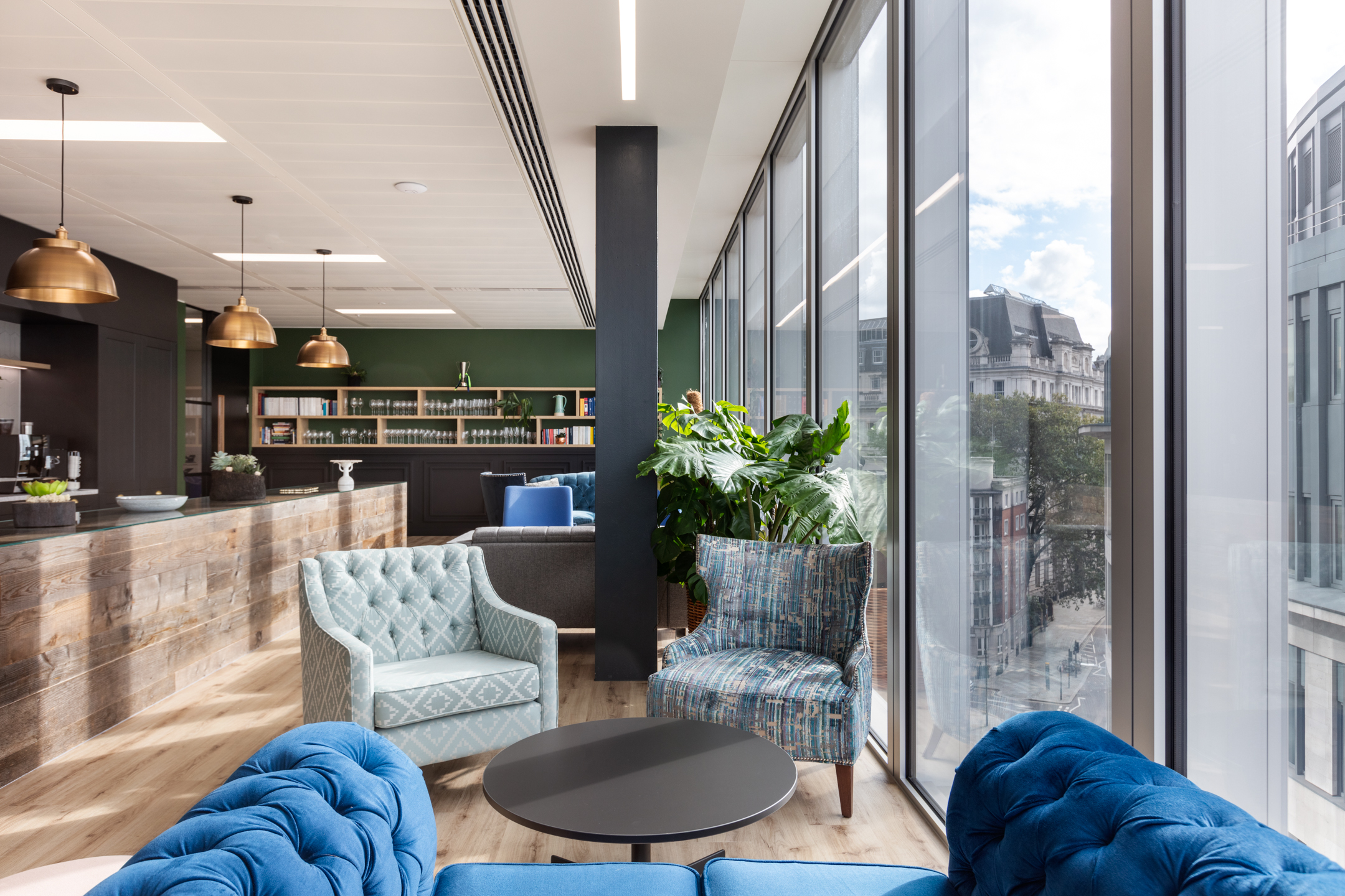 finnCap teapoint breakout space with lounge furniture by Platfform, showcasing patterned armchairs, a timber bar and full-height glazing overlooking the city.