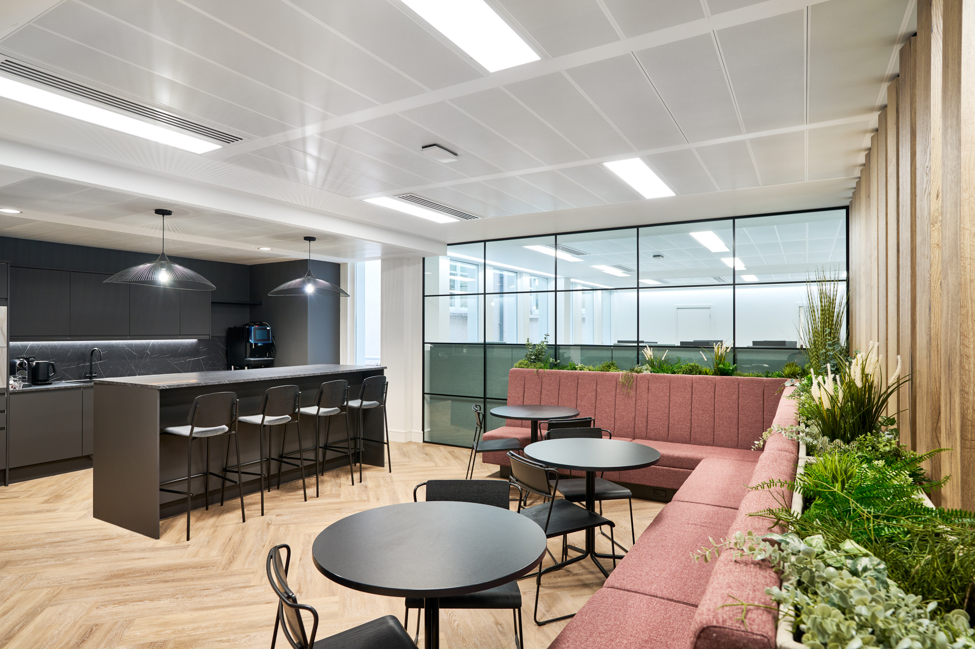 The redesigned teapoint at Gemserv’s workspace features full-height glazing, timber slats, and built-in banquette seating, creating a modern yet cohesive design by Platfform.