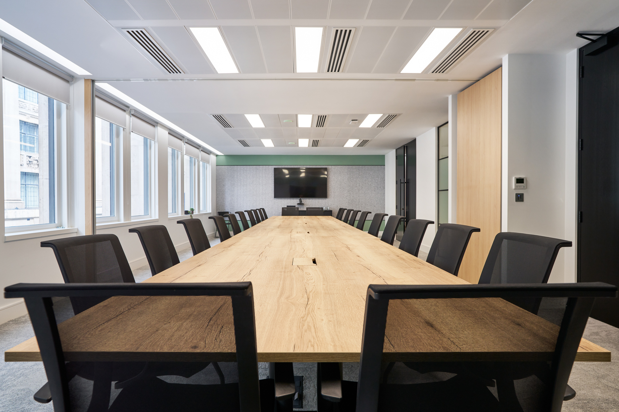 Spacious boardroom in Gemserv’s workspace by Platfform, featuring a long wooden table, ergonomic chairs, a wall-mounted screen for presentations, and folding walls to divide the meeting room to Gemserv’s growing needs.