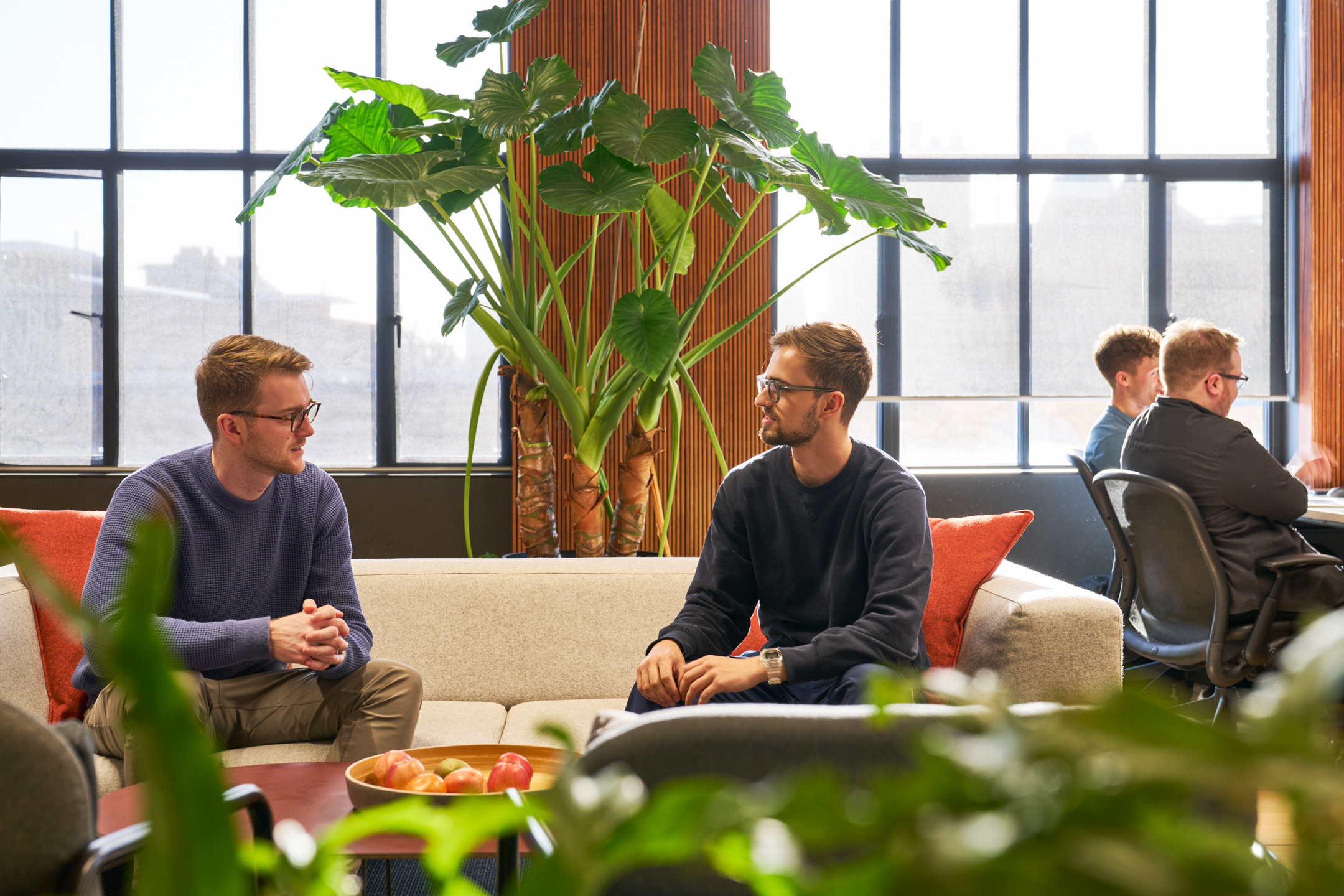 Employees chatting in a relaxed seating area designed by Platfform, featuring lush greenery and comfortable furniture.