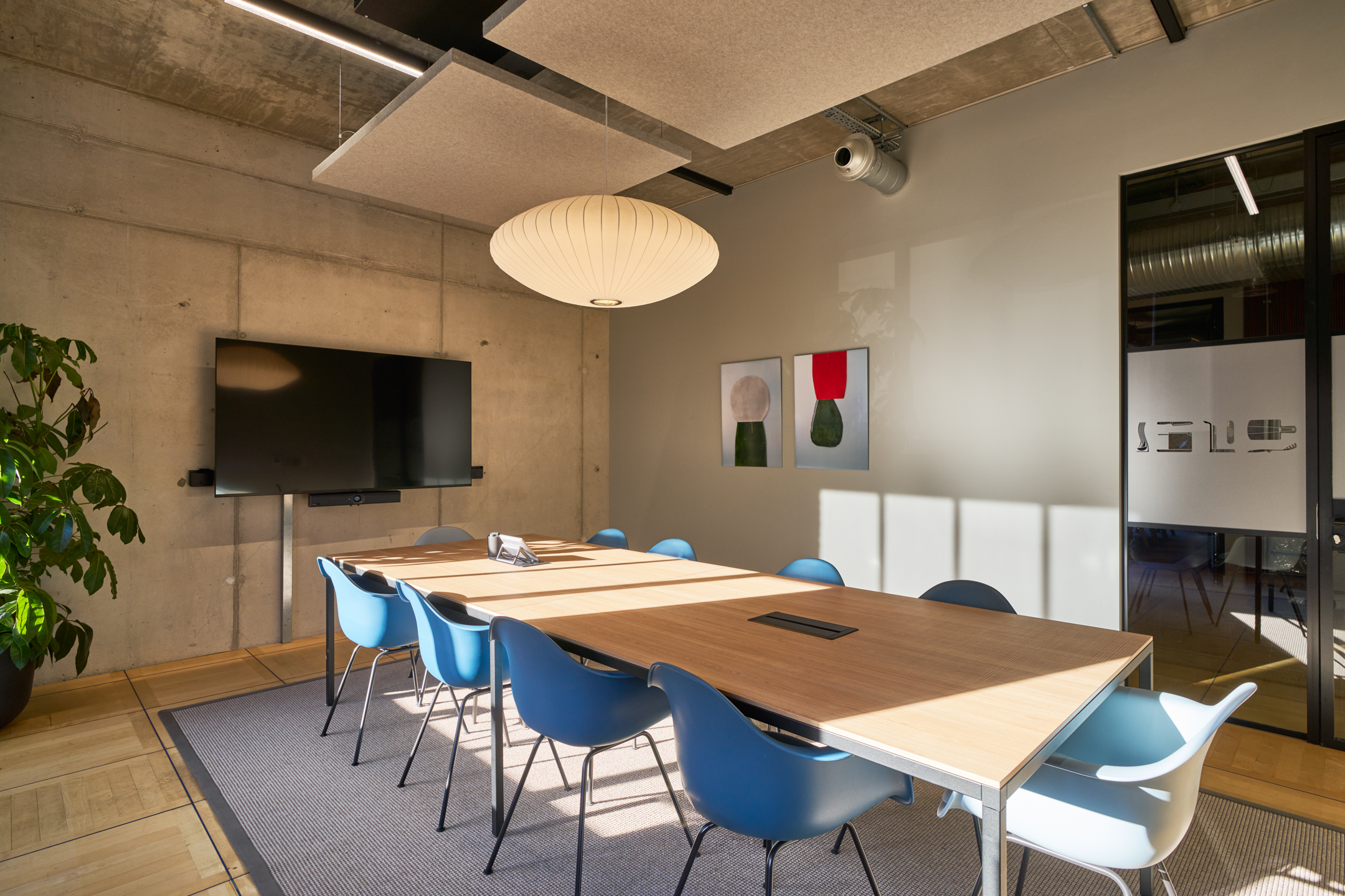 Contemporary boardroom featuring acoustic ceiling panels, sleek furniture, and natural light enhancing the space.