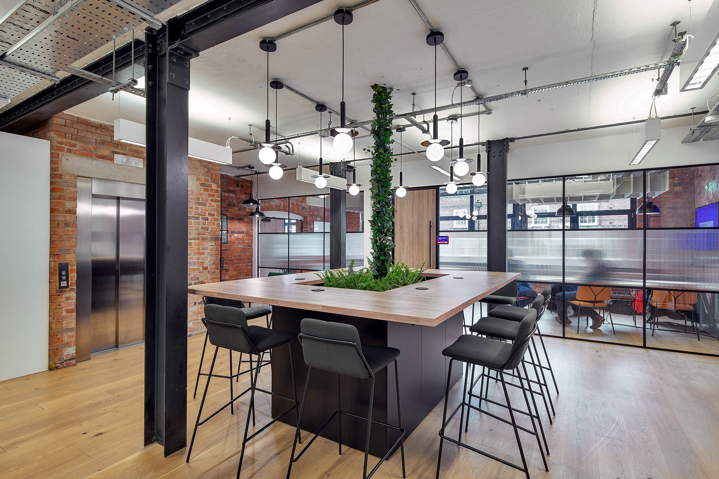 Creative workspace at the Kin & Carta office by Platfform, featuring an open-plan layout with greenery and a central collaboration island.