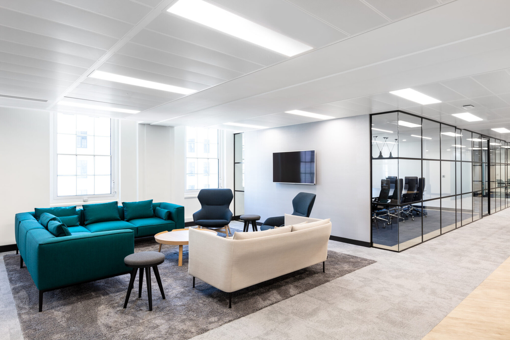 A spacious breakout area with teal sofas and minimalist furnishings, reflecting the brand values of Literacy Capital and Bookmark.