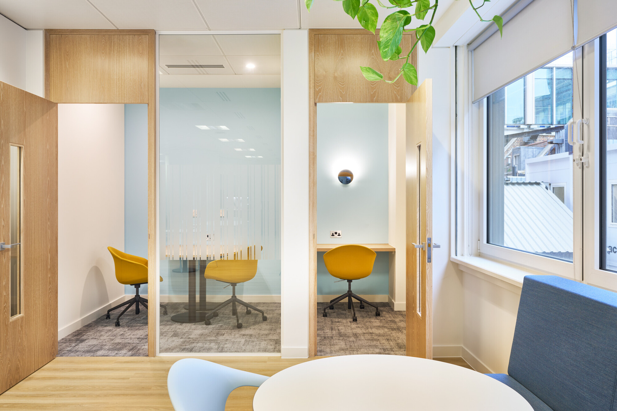 Stylish office interior with modern wooden doors and glass meeting rooms, featuring yellow chairs and minimalist design for Tech UK.