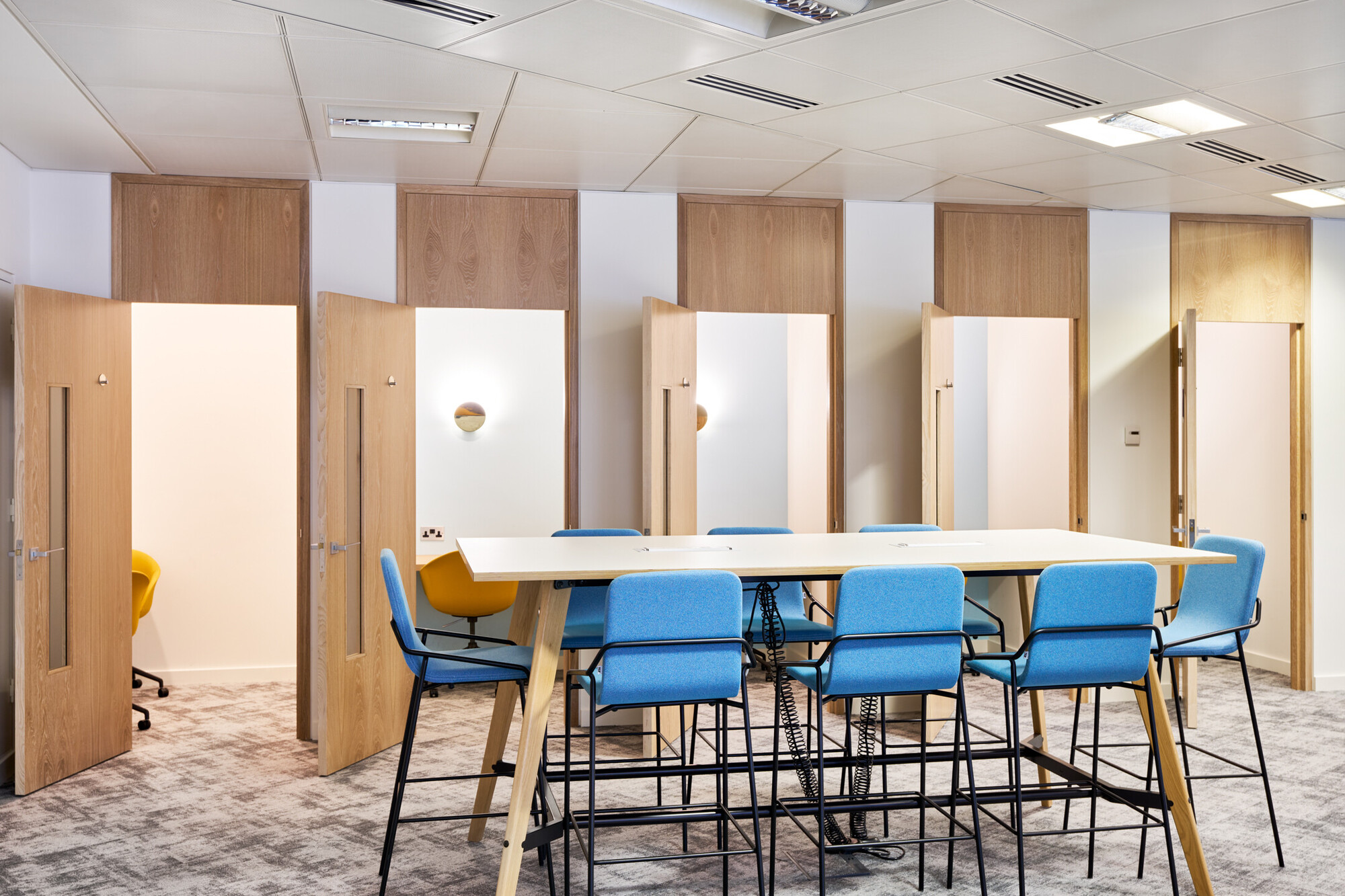 Bright and spacious Tech UK office with furniture by Platfform, showcasing an open workspace with blue and yellow seating and contemporary lighting.