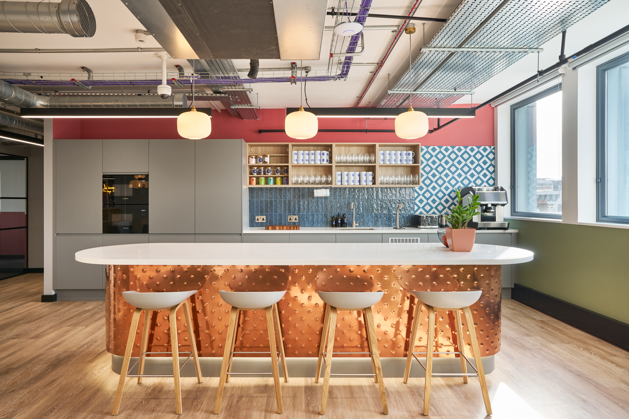 Stylish teapoint at Work.Life Waverly House by Platfform, featuring a textured copper island, bold tile backsplash, and ample natural light for a vibrant setting.