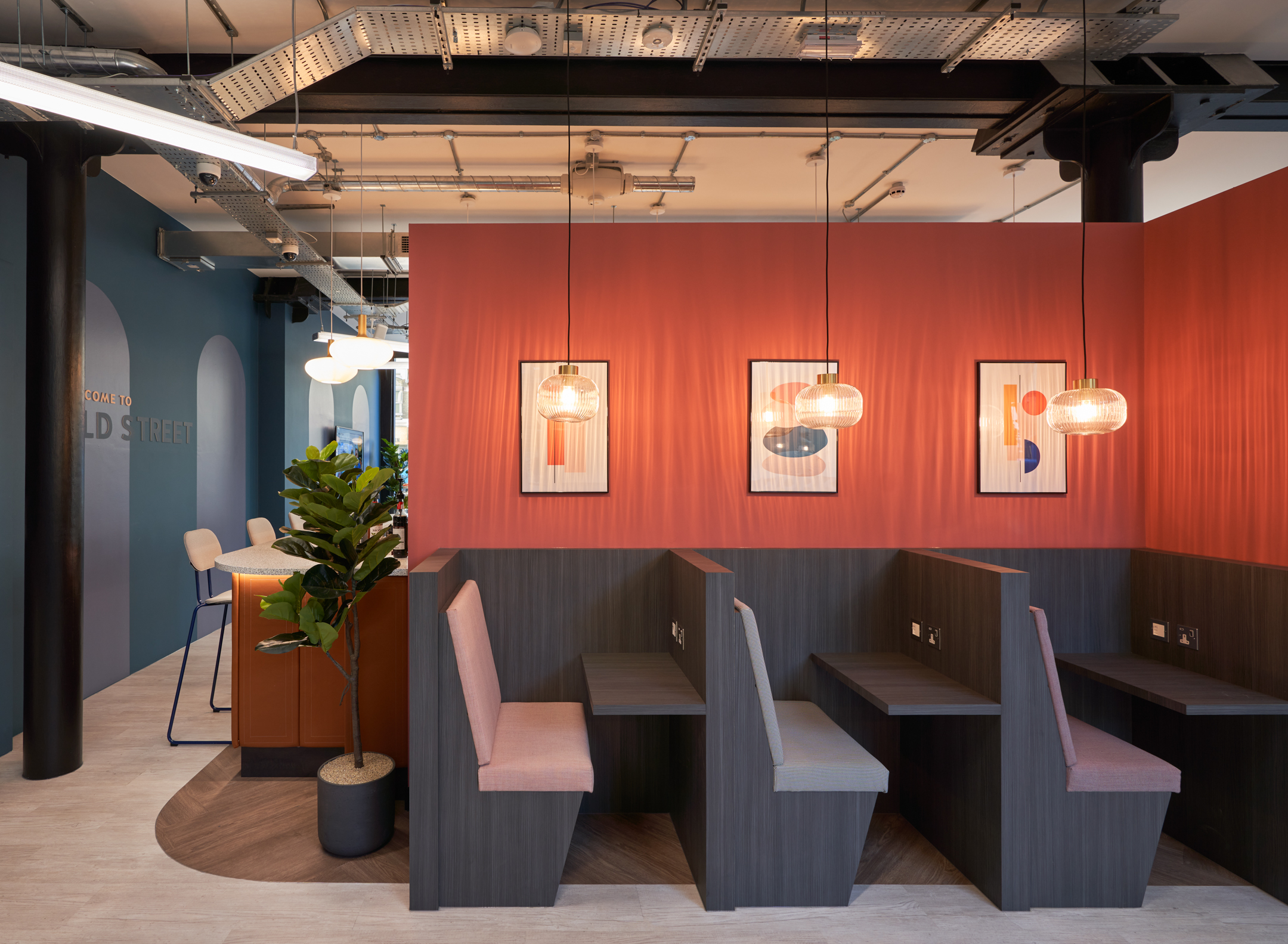 Private booth seating at Work.life Rivington House by Platfform, with warm orange accents and contemporary lighting, perfect for focused work in a stylish workspace.