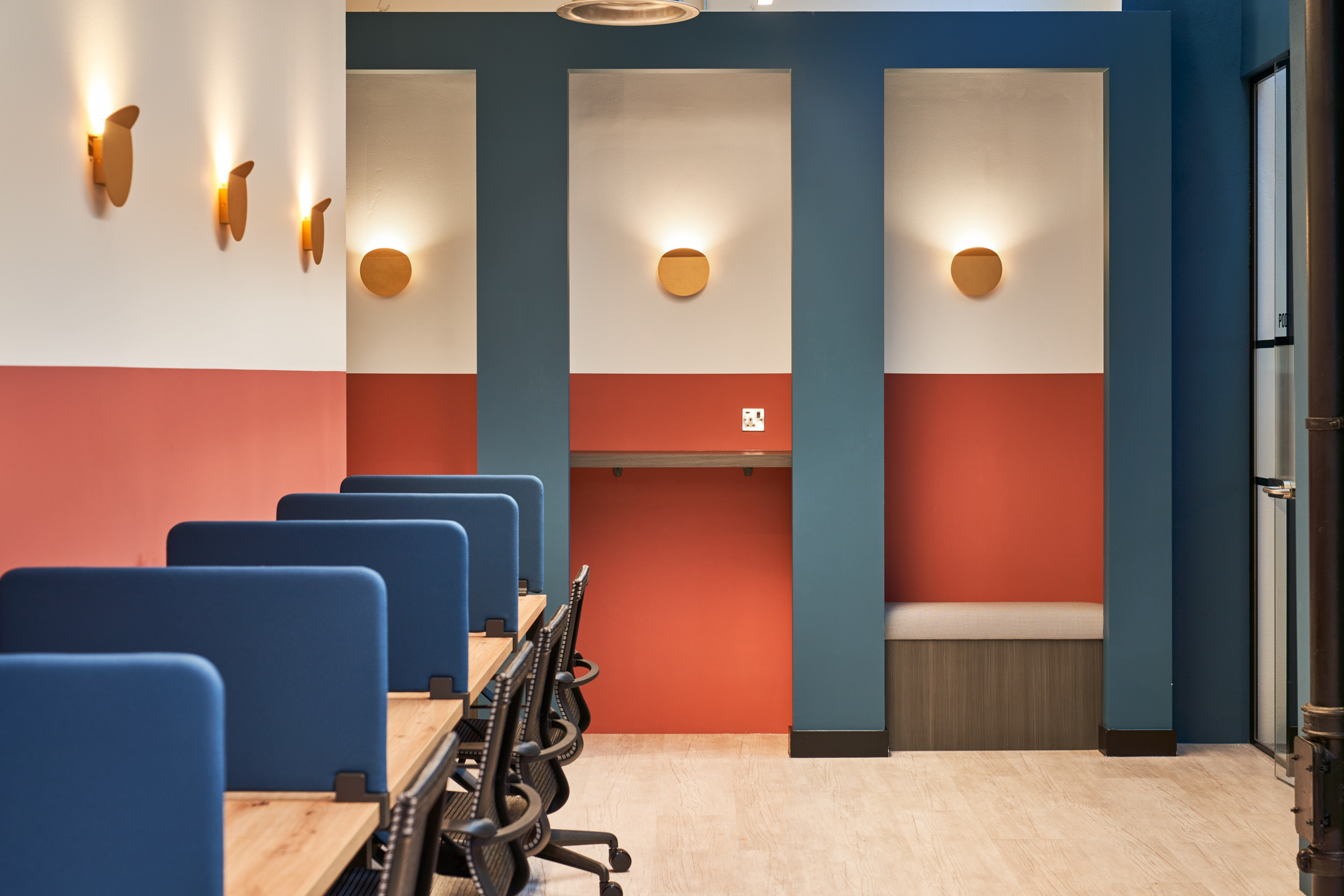 Dedicated desk space at Work.life Rivington House, with comfortable chairs, blue privacy panels, and bold colour accents, offering a productive workspace designed by Platfform.