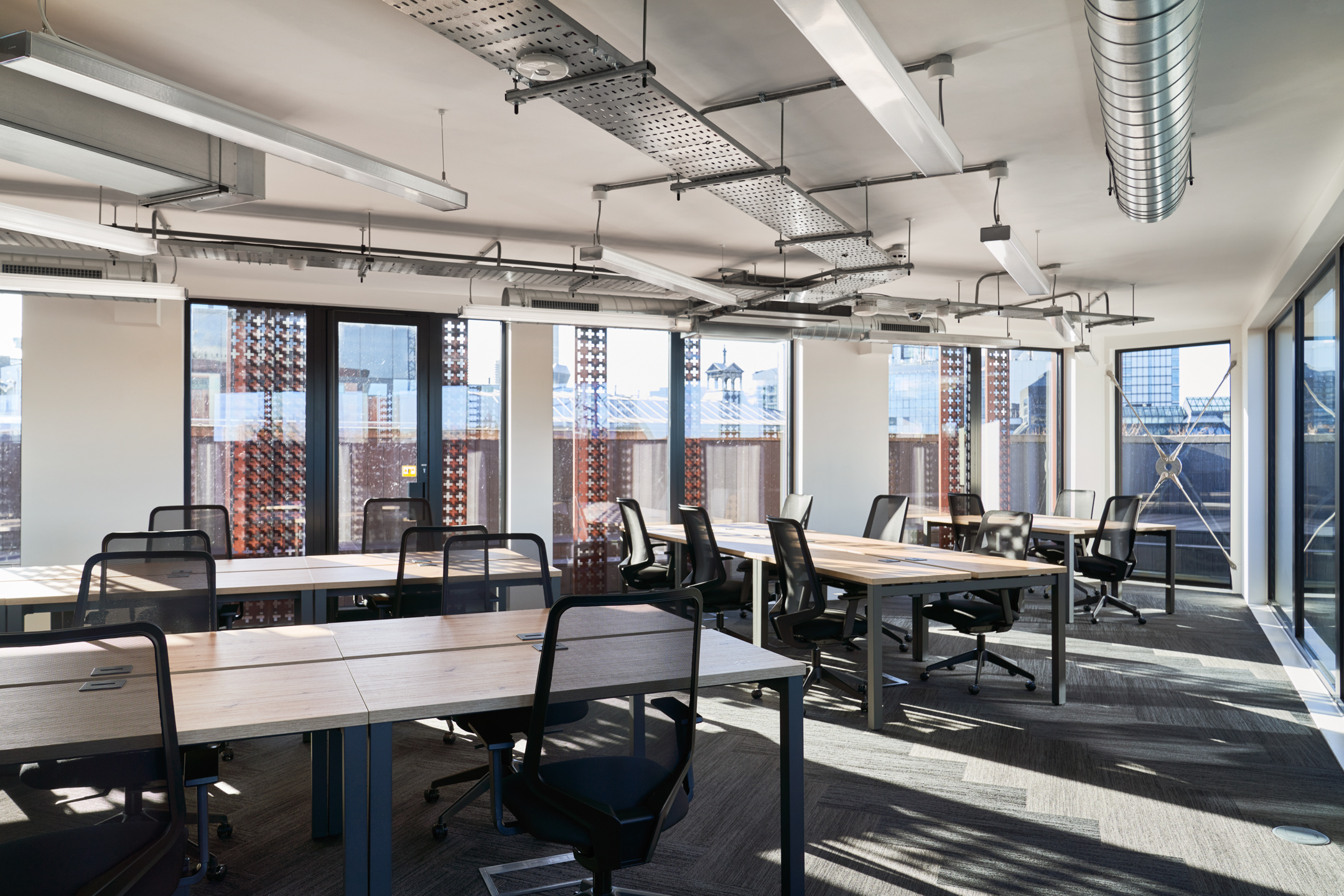 A bright and spacious open-plan office at Work.life Rivington House, designed by Platfform, with natural wood desks and expansive windows providing a productive and inspiring workspace.