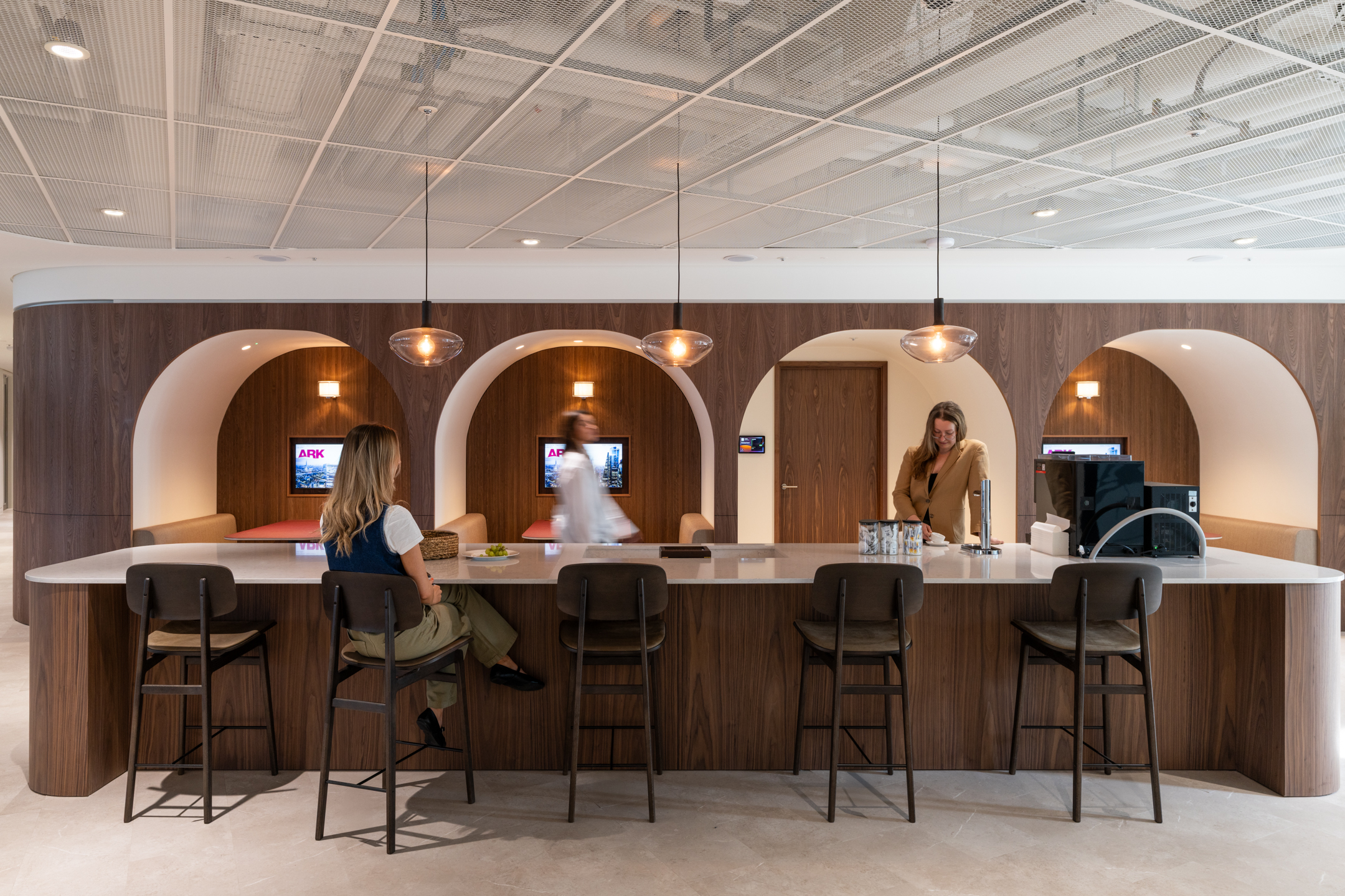 Ark Syndicate breakout bar with curved wood panelling, booth seating and high stools designed for casual chats and coffee breaks.